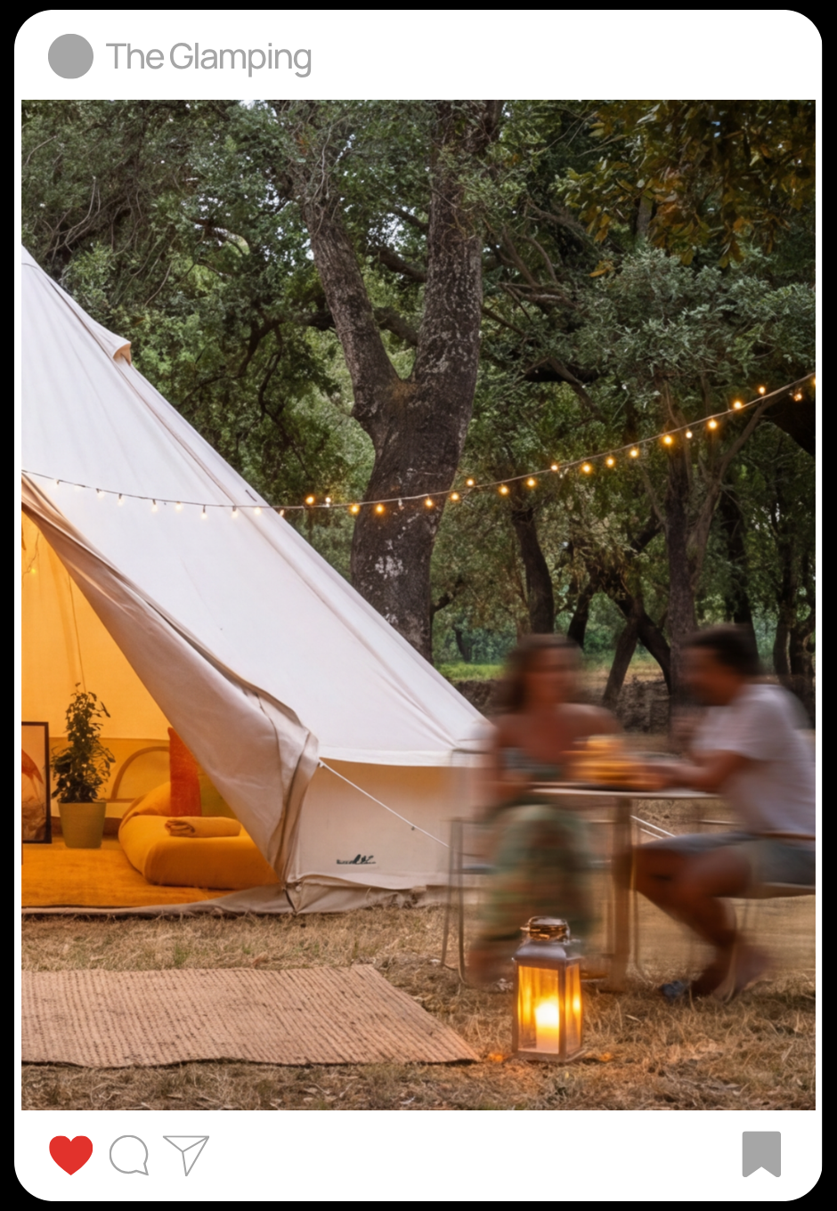 Escena campestre al atardecer con una tienda de campaña, luces decorativas y parejas comiendo en una mesa, con fondo de árboles y un ambiente acogedor.