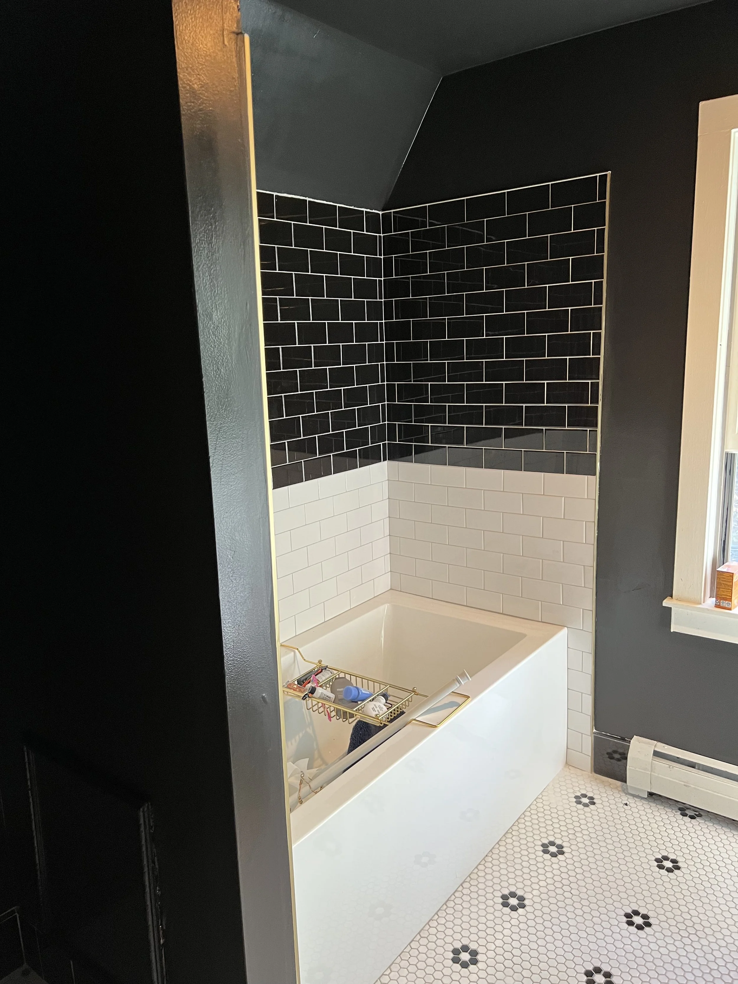 Bathroom with black and white tile wall, white bathtub, and black and white patterned floor.
