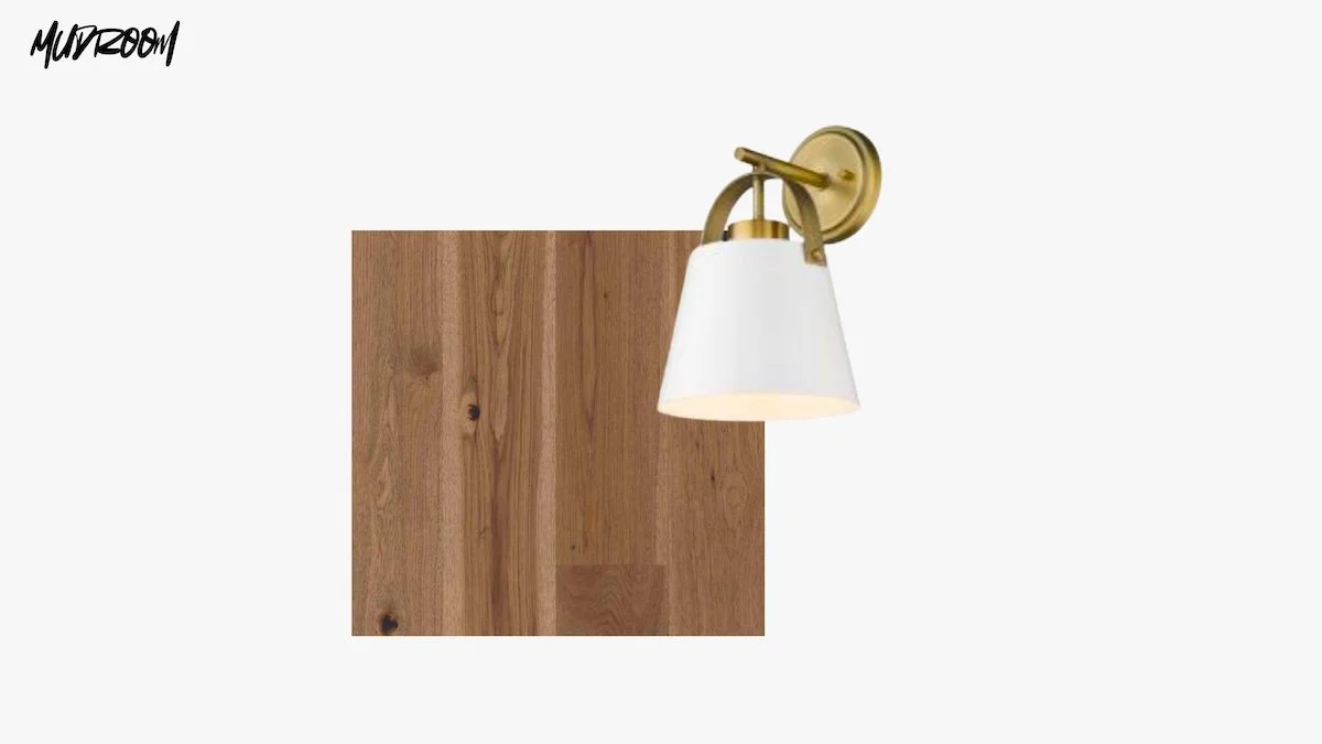 Wall-mounted light fixture with a white lampshade and brass details, against a plain white wall.