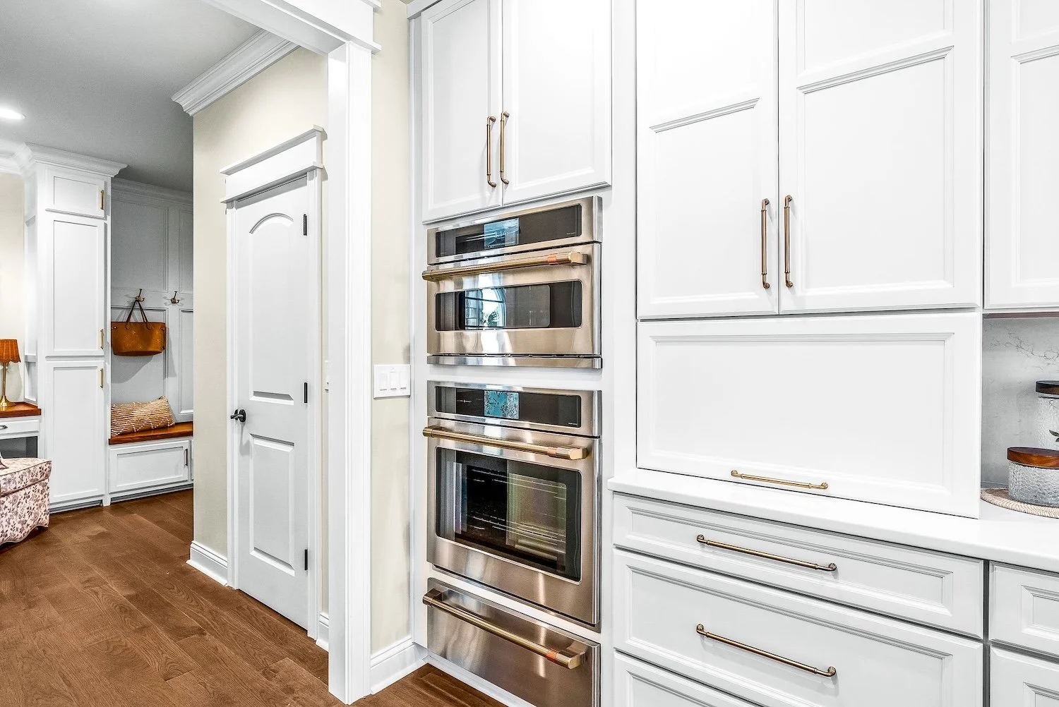 Kitchen with white cabinets, stainless steel built-in ovens, and hardwood floors.