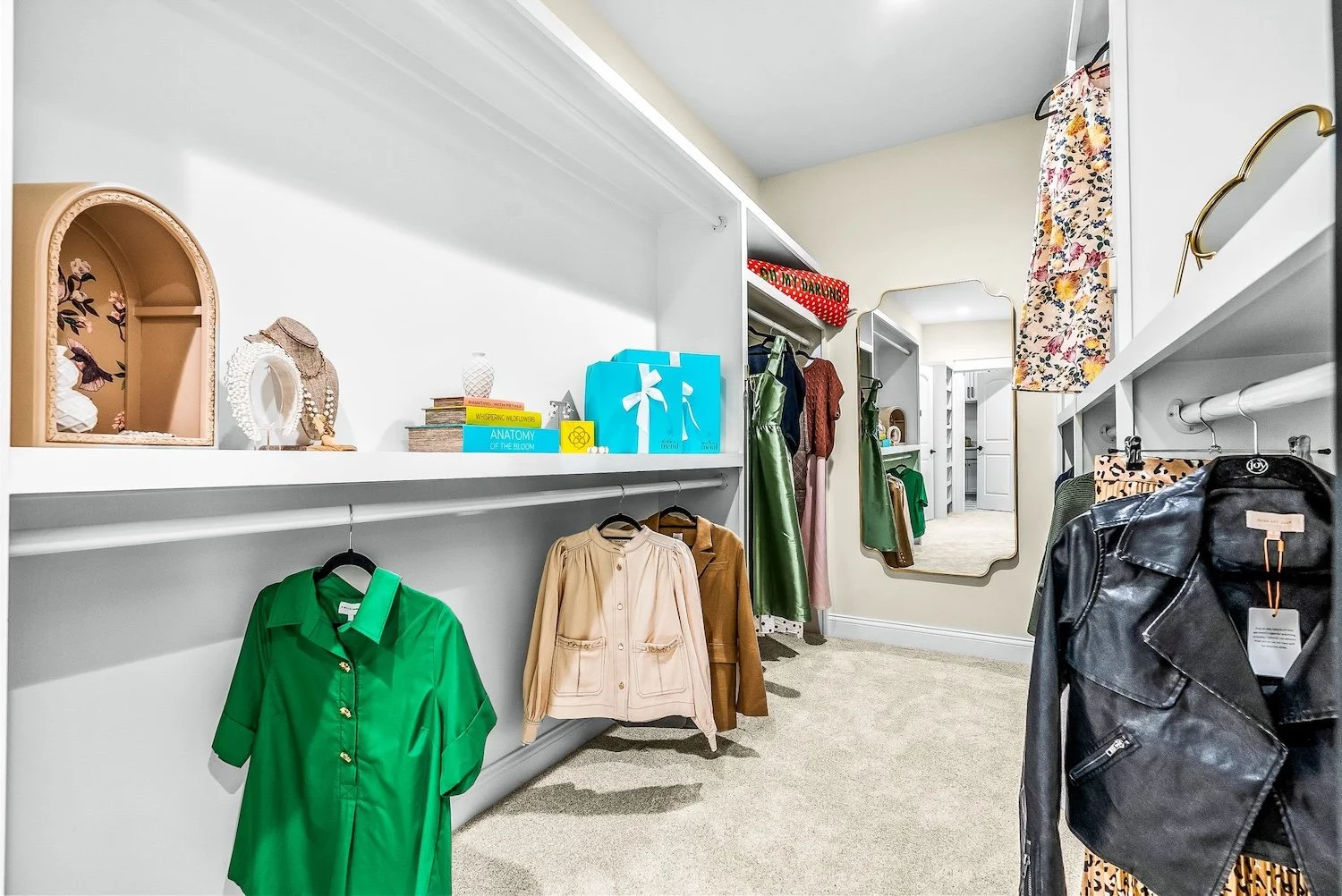 Walk-in closet with clothing, accessories, and decorative items on shelves and hanging rods, with a full-length mirror on the wall.