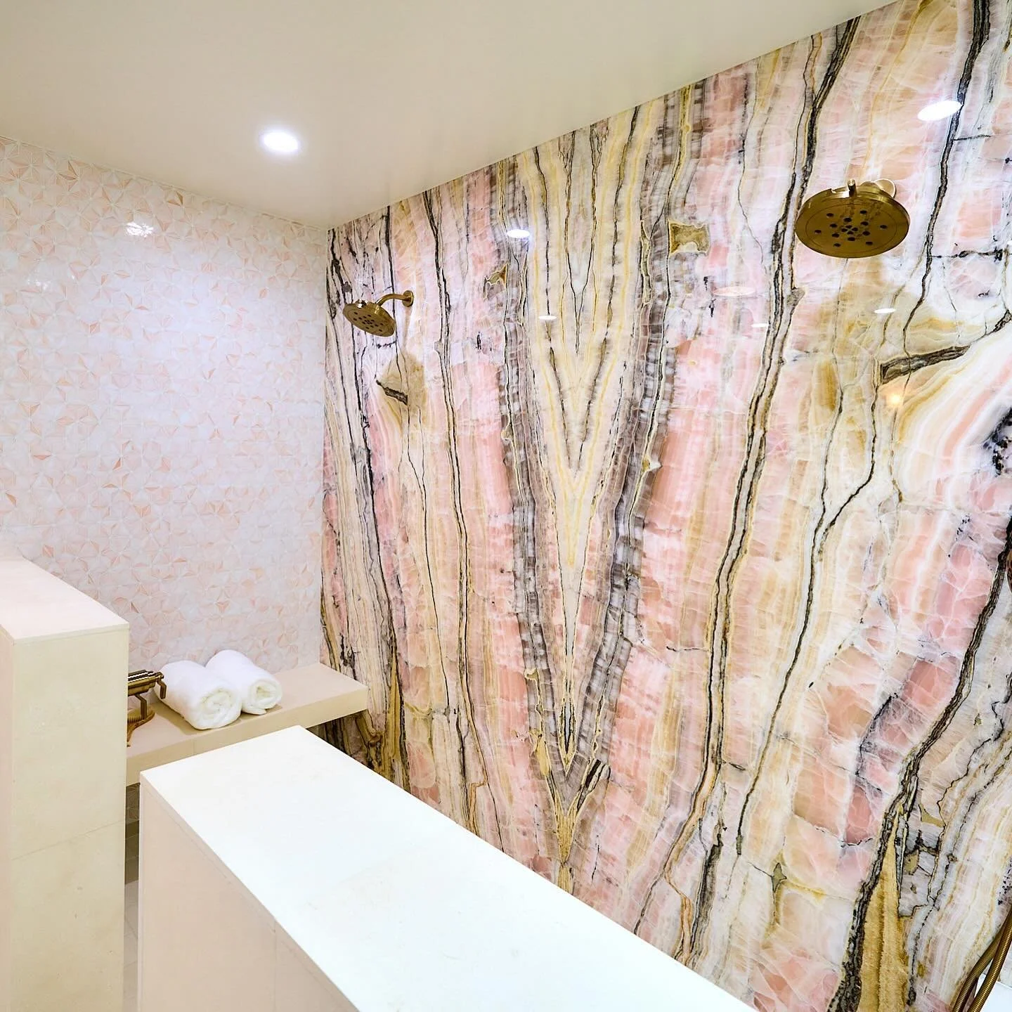 Pretty in pink bath with onyx slabs, blush glass tile and limestone
Tile: @designcollaborativeusa  and @oceansideglasstile 
 Slabs: @formationstone 
install: @pietradlusso_tile_n_stone 
#kellywearstlerlighting
#Brizo #pinkbathrooms #doubleshower #ony