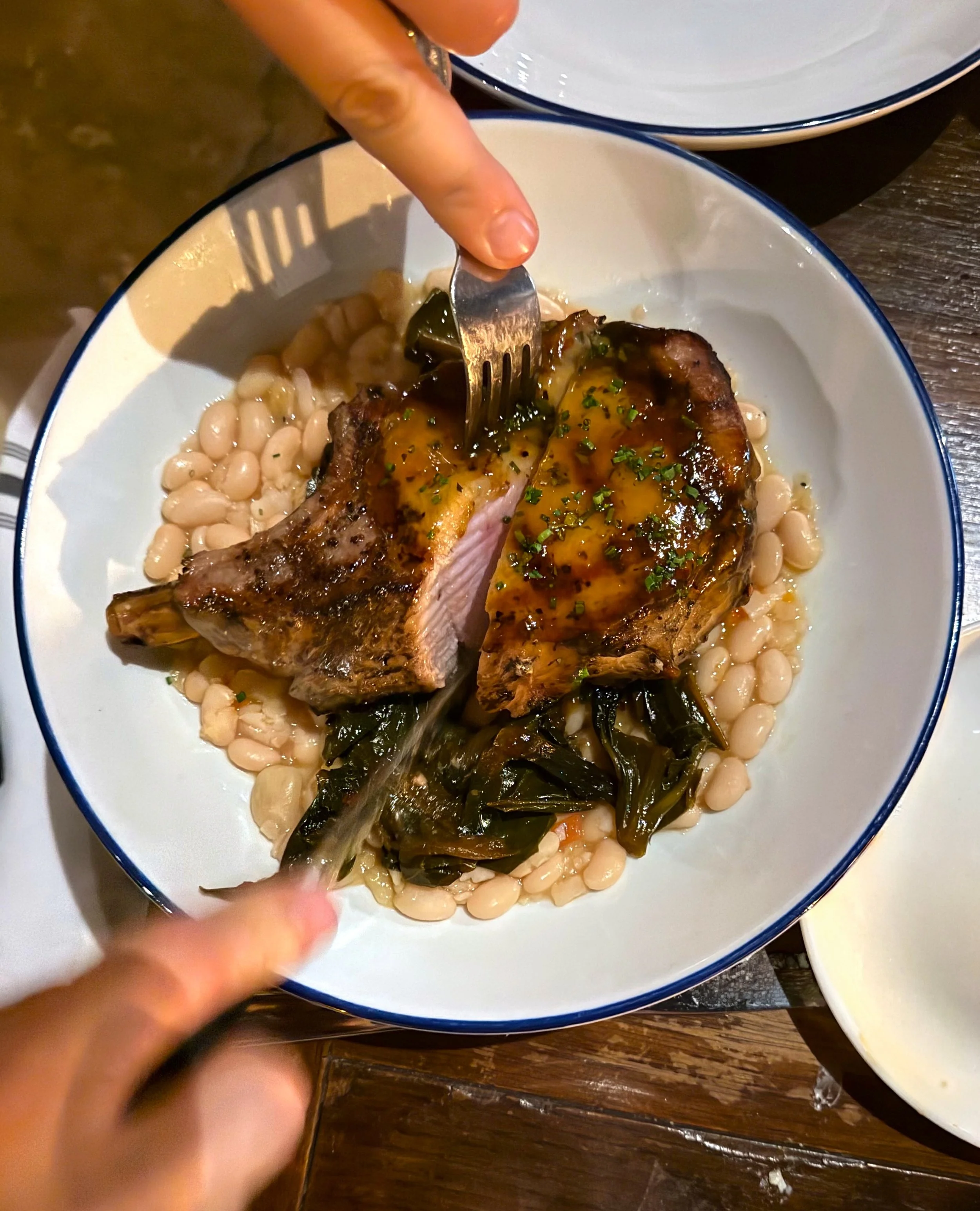 The peach glazed pork chop ALMOST looks too good to eat!⁠
⁠
Our pork chop is pit smoked and grilled over a hickory wood-fired grill topped with a chili peach glaze, then served over white beans and collard greens. 😋⁠
⁠
#factoryatfranklin #franklintn