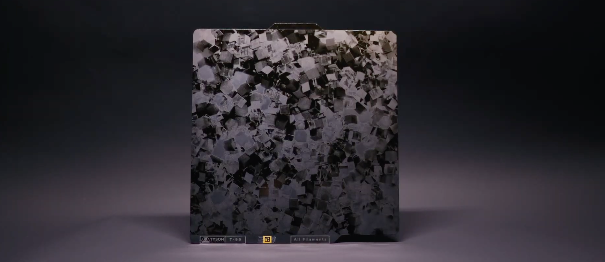 A rectangular sheet with a textured pattern of small, irregular, silver, and black squares.