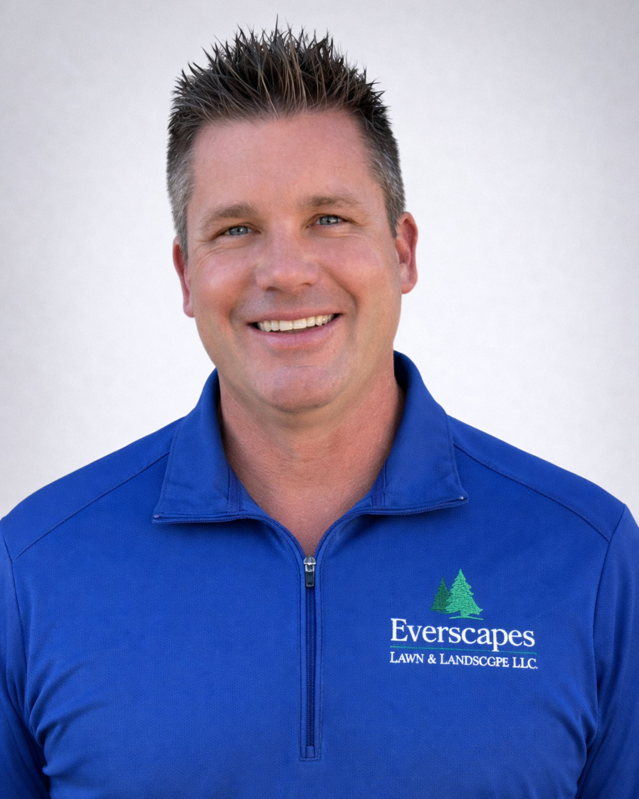 Owner of Everscapes Landscaping, Eric Wymer smiling on a grey background.