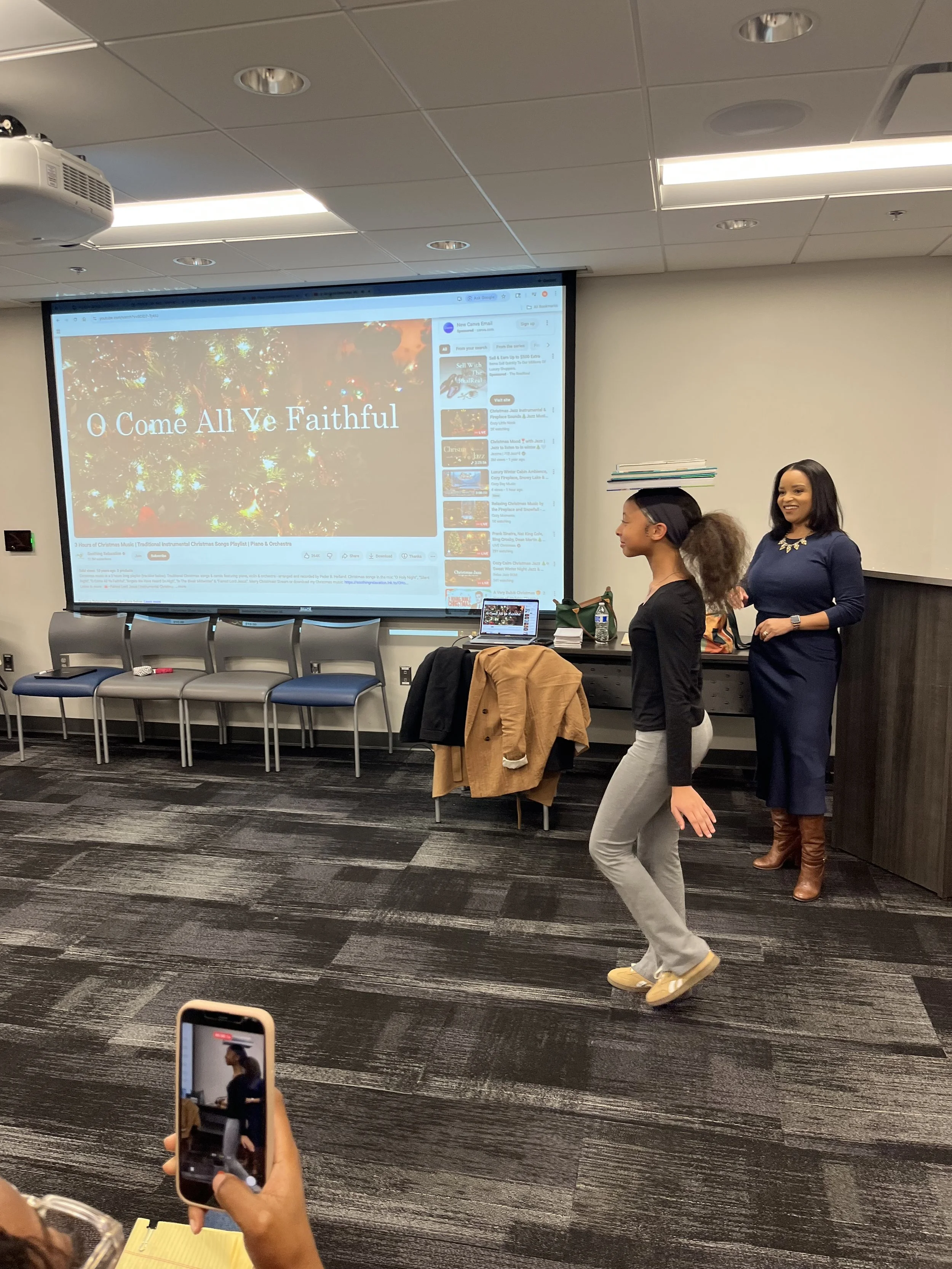 Debutante walks with book on head to practice posture, balance, and controlled movement. Pictured with Etiquette Coach- Margo Gray