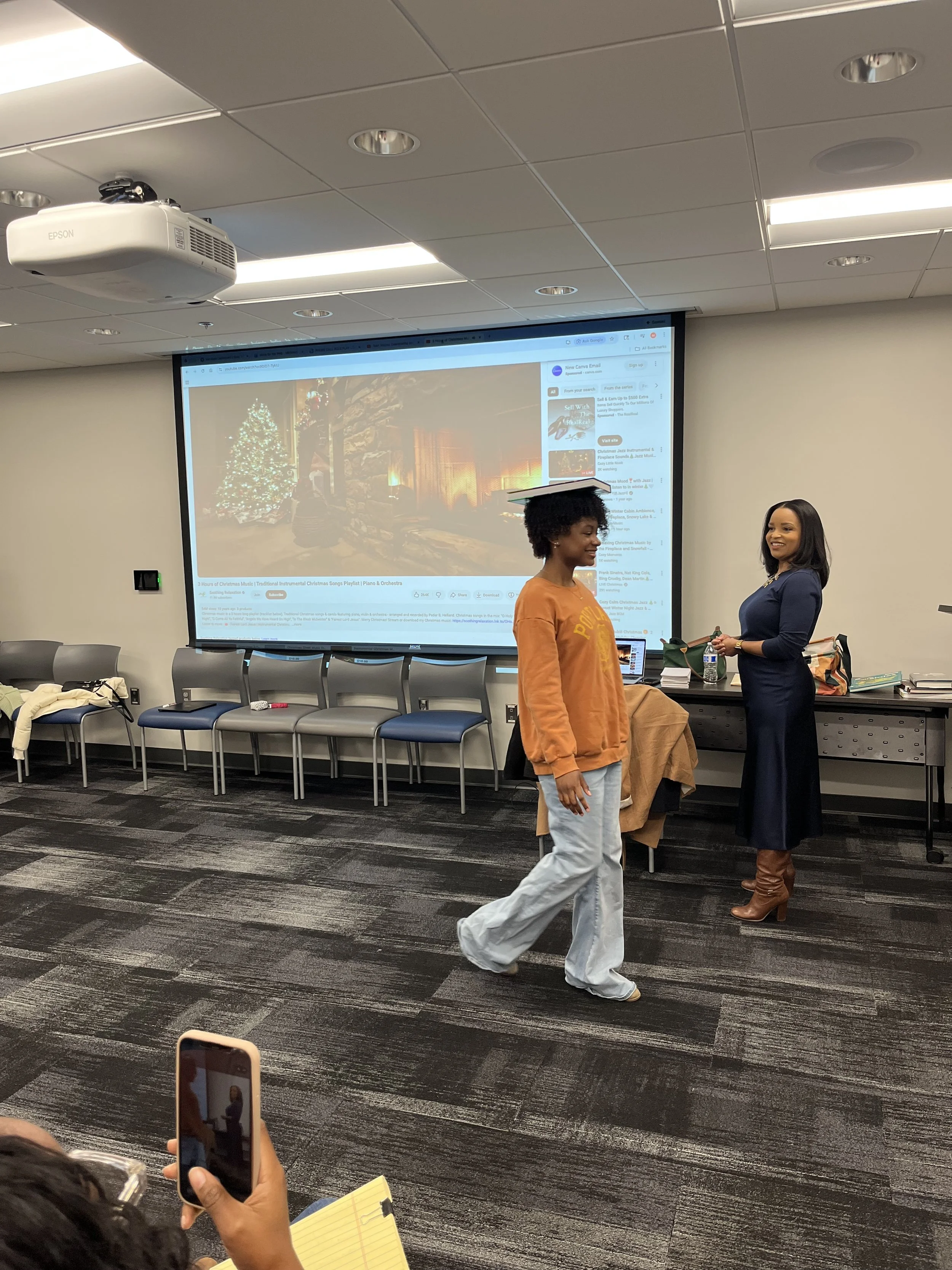 Debutante walks with book on head to practice posture, balance, and controlled movement. Pictured with Etiquette Coach- Margo Gray