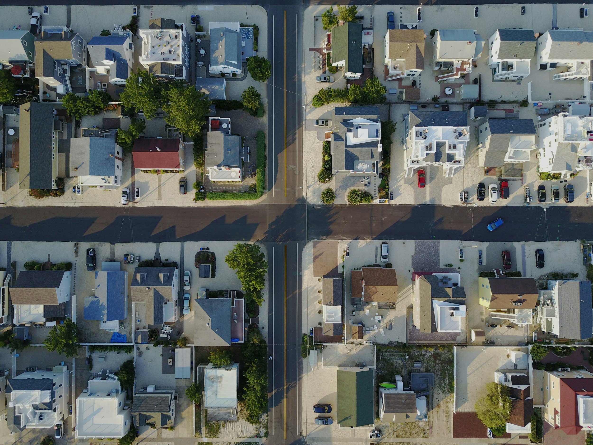 Aerial view of a residential neighborhood showing houses, trees, and parked cars.