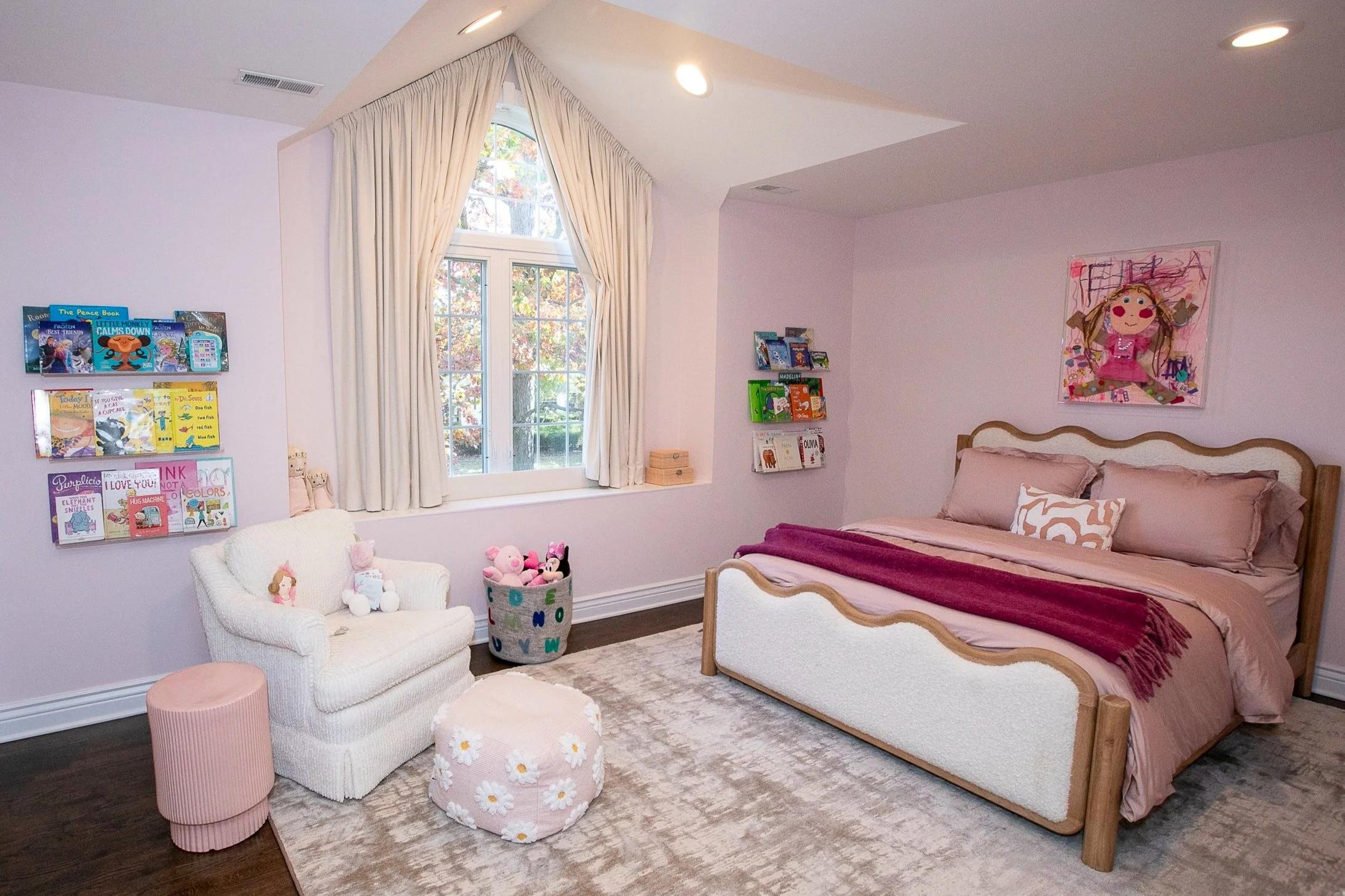 The focal point of this room is the framed self-portrait above the bed, made by the child herself, it brings a sense of personality and warmth to the decor of the room. The room represents a child-friendly space filled with creativity and imagination