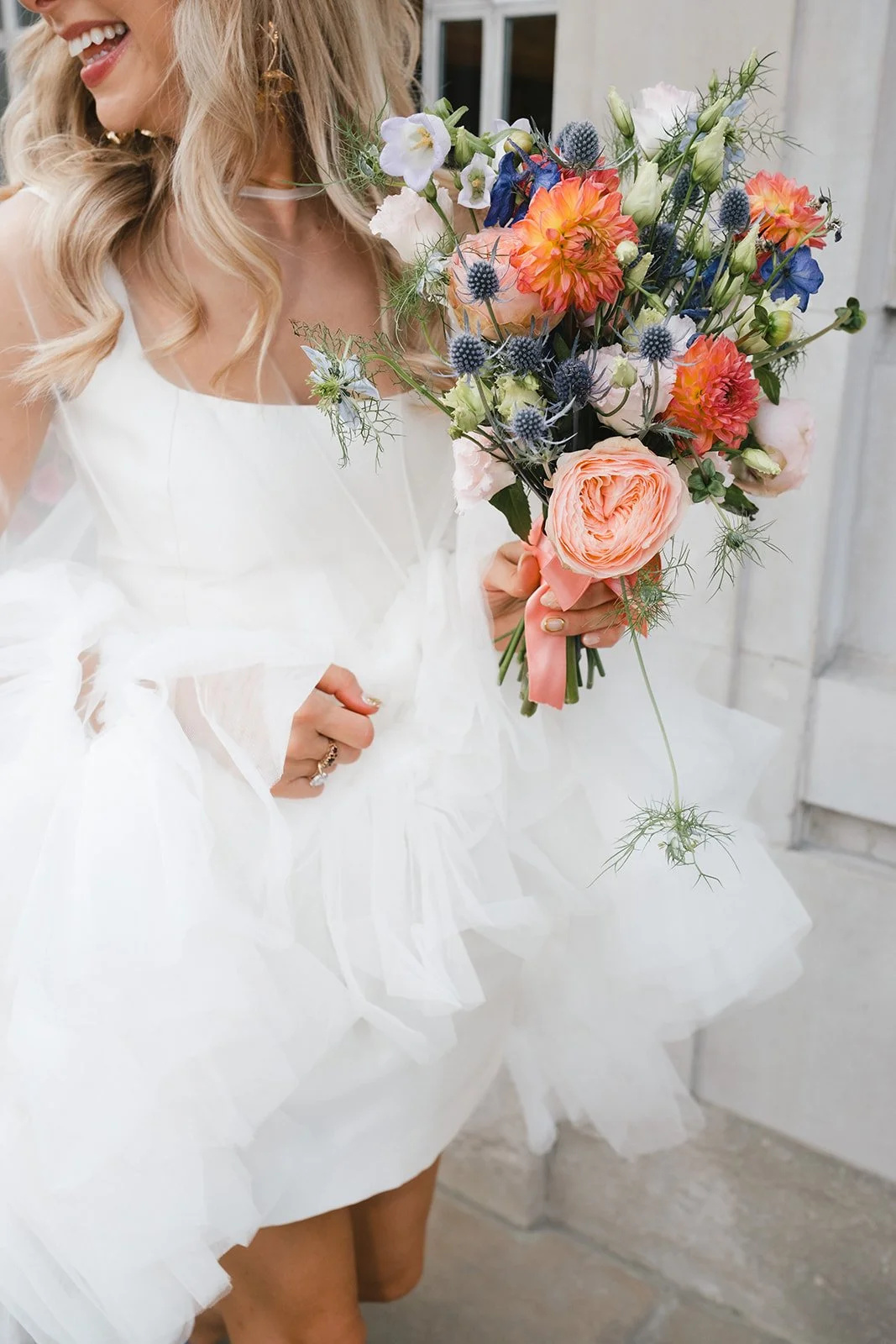 Woman in a white dress holding a colorful bouquet of flowers.