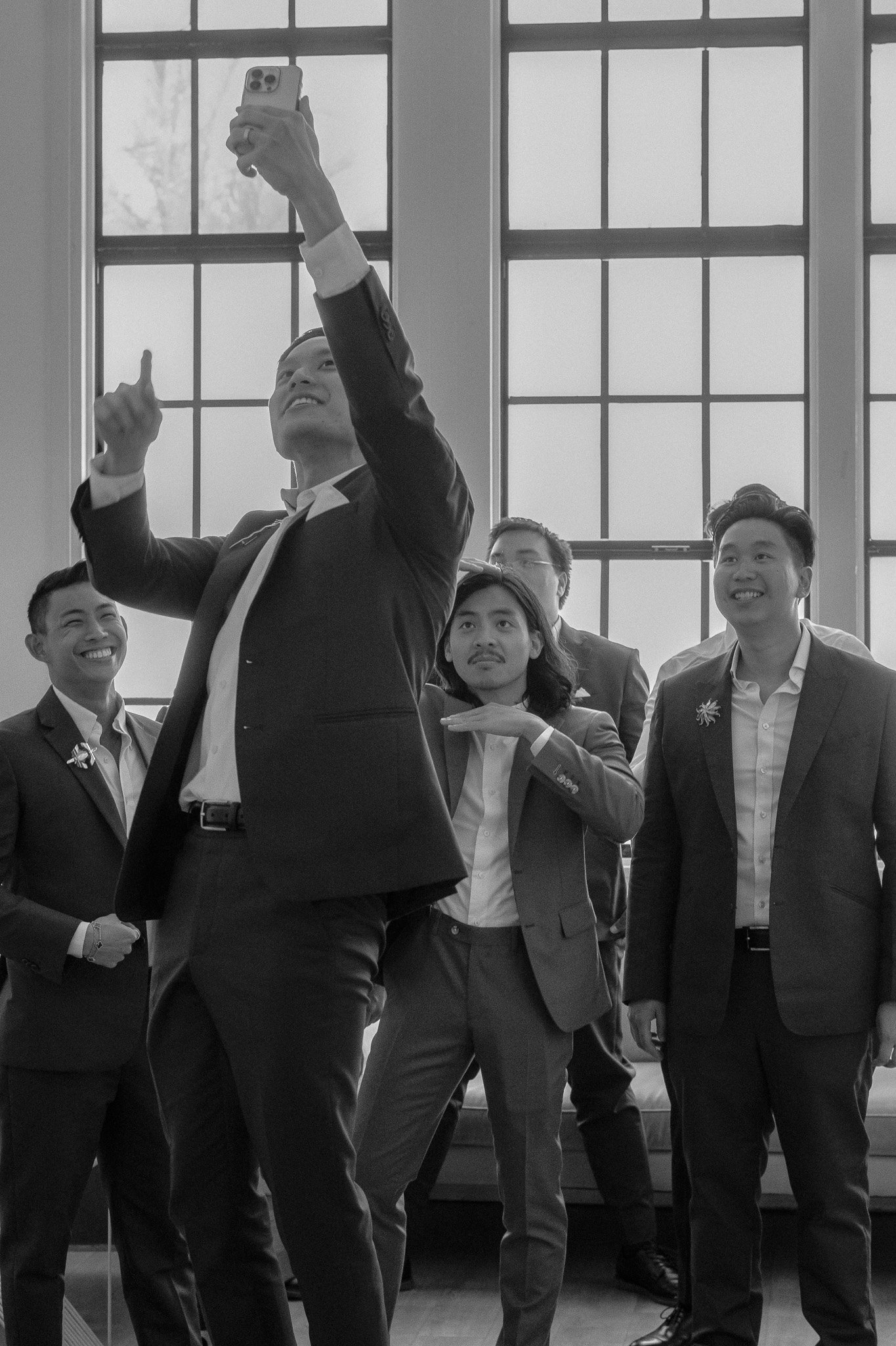 Group of men in suits taking a selfie indoors.