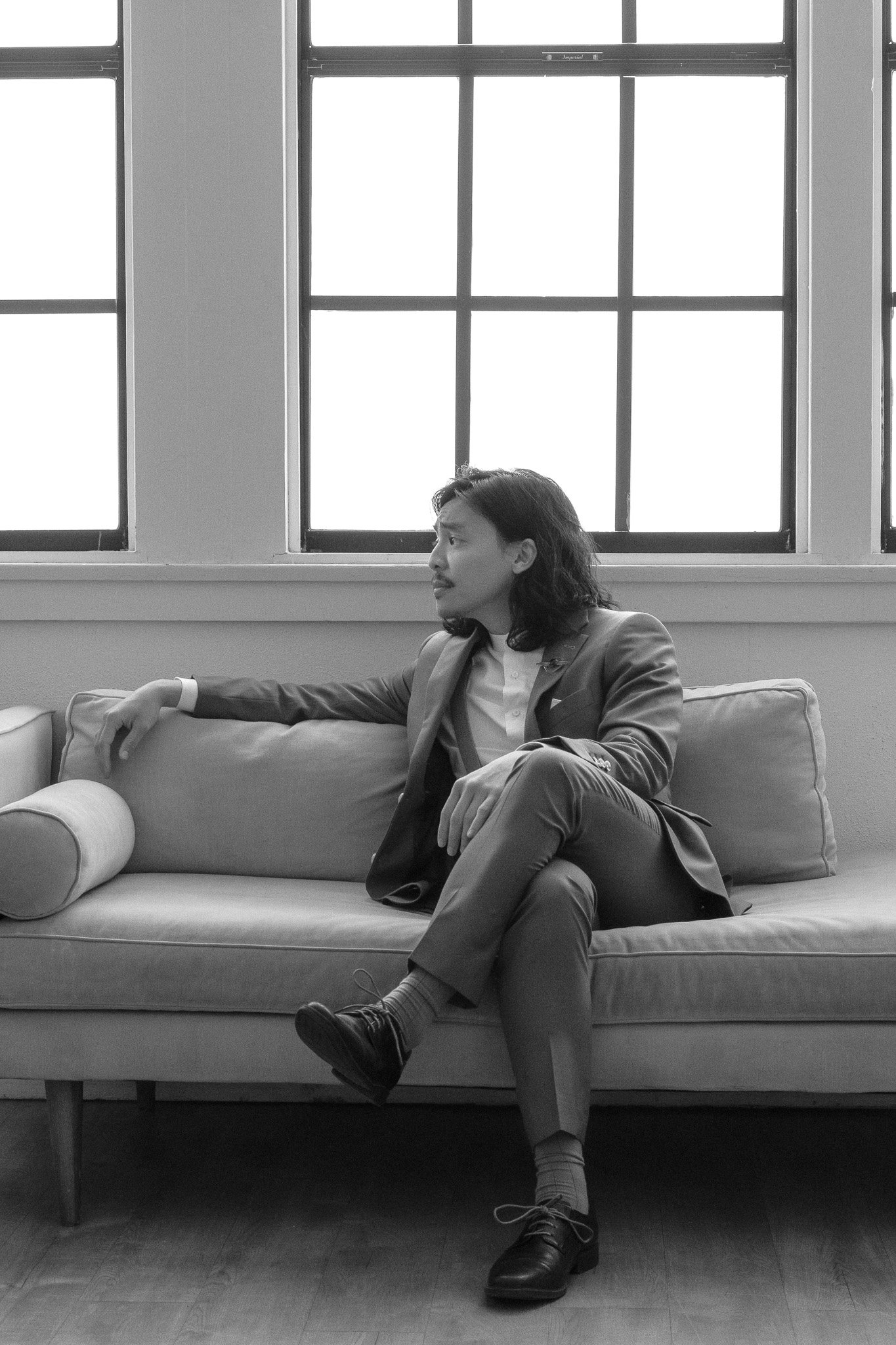 Man in suit sitting on a sofa against large windows