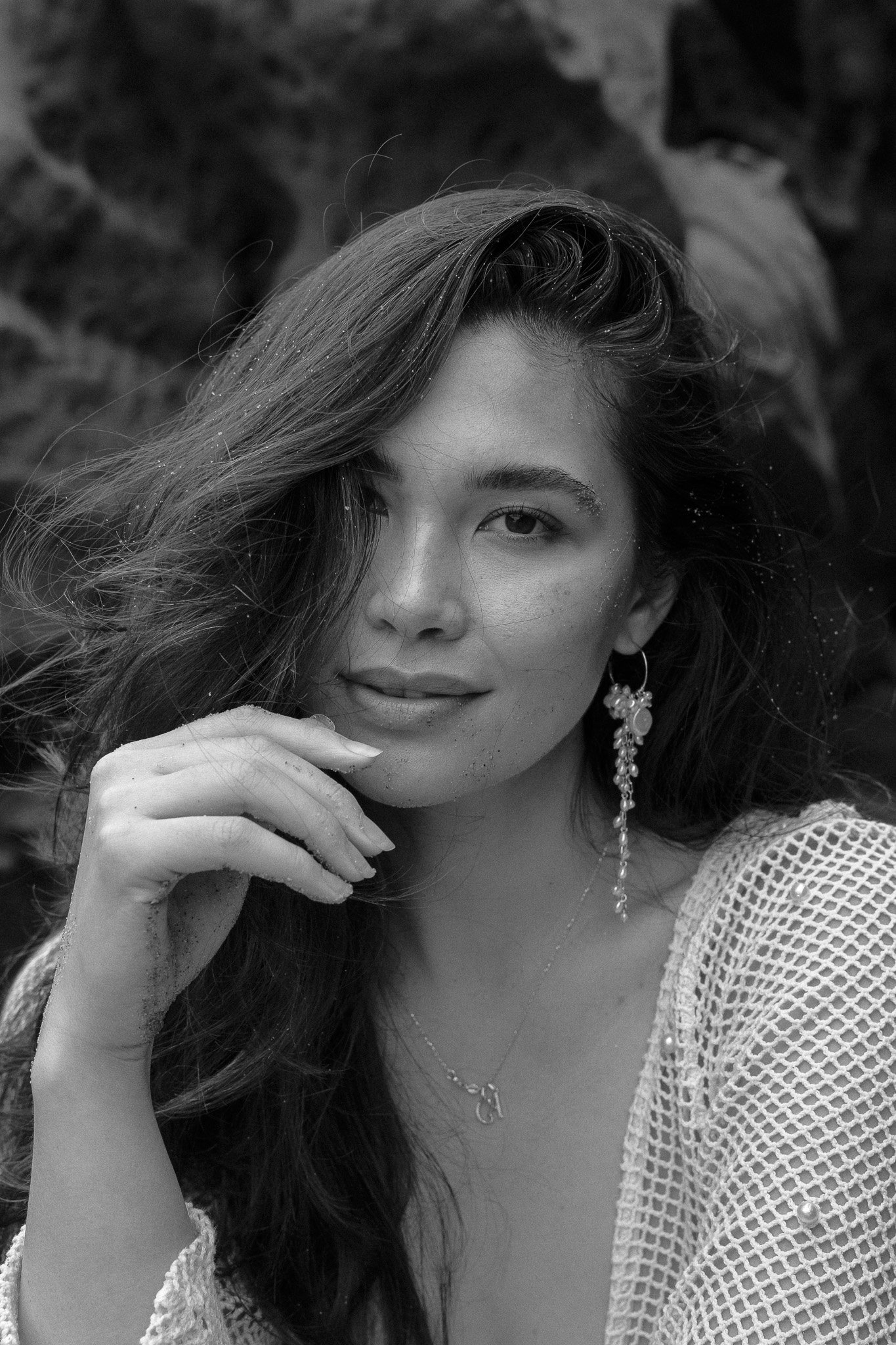 Black and white portrait of a woman with long hair, wearing an earring and a netted top.
