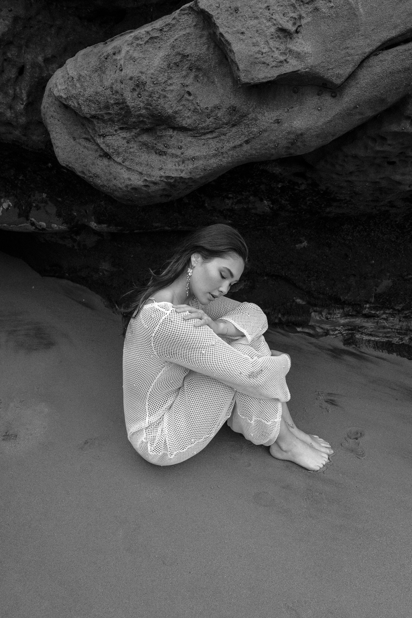 Woman sitting on sand under a rock formation