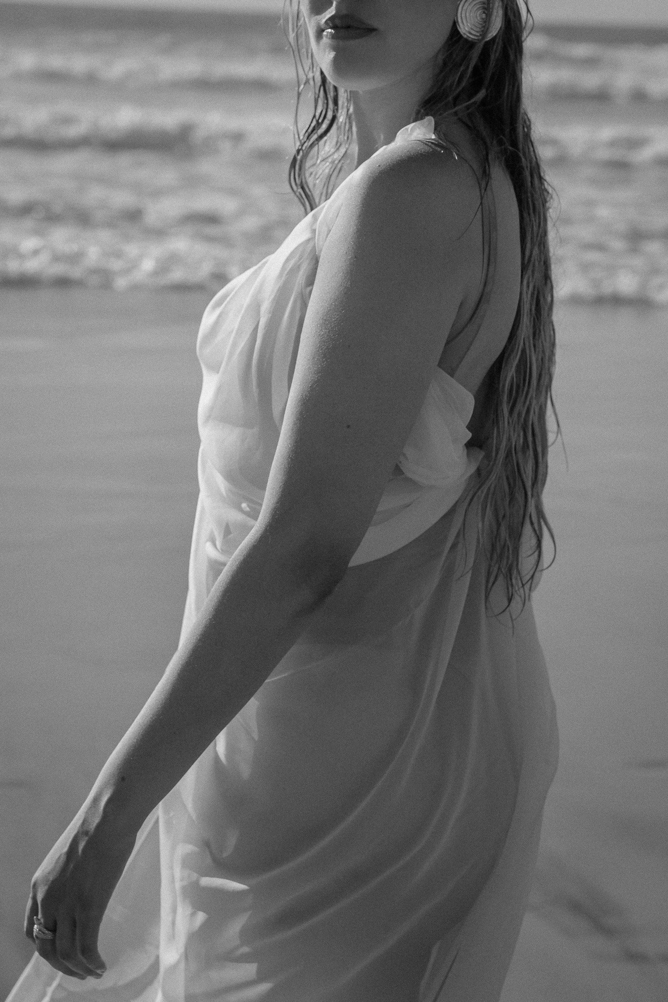 Black and white photo of a woman in a flowing dress on a beach.