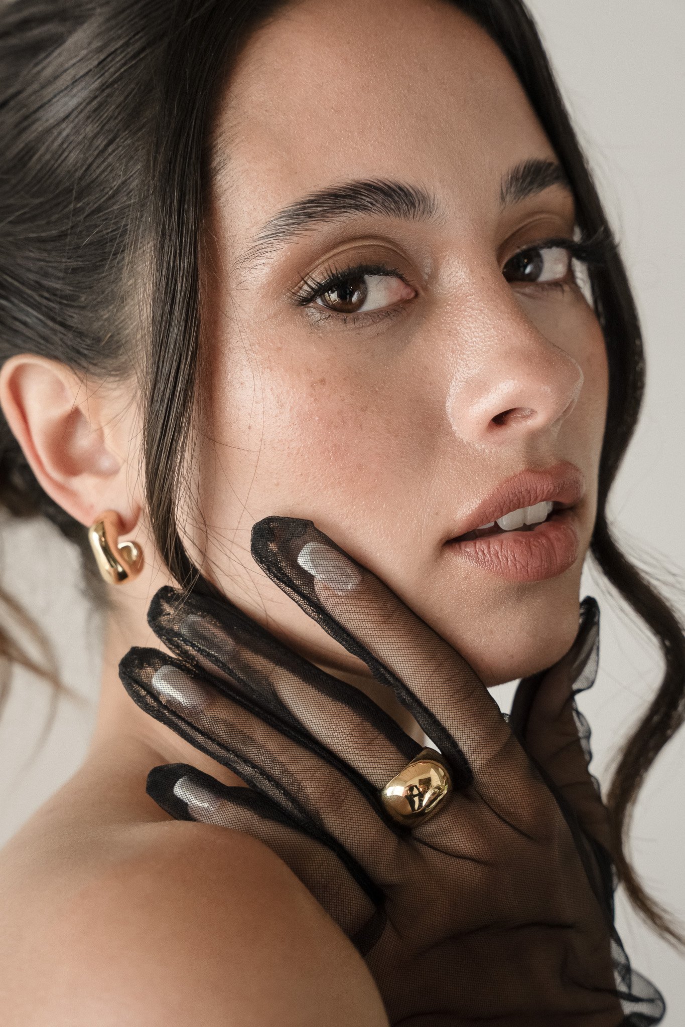 Close-up of a woman wearing black lace gloves and gold jewelry