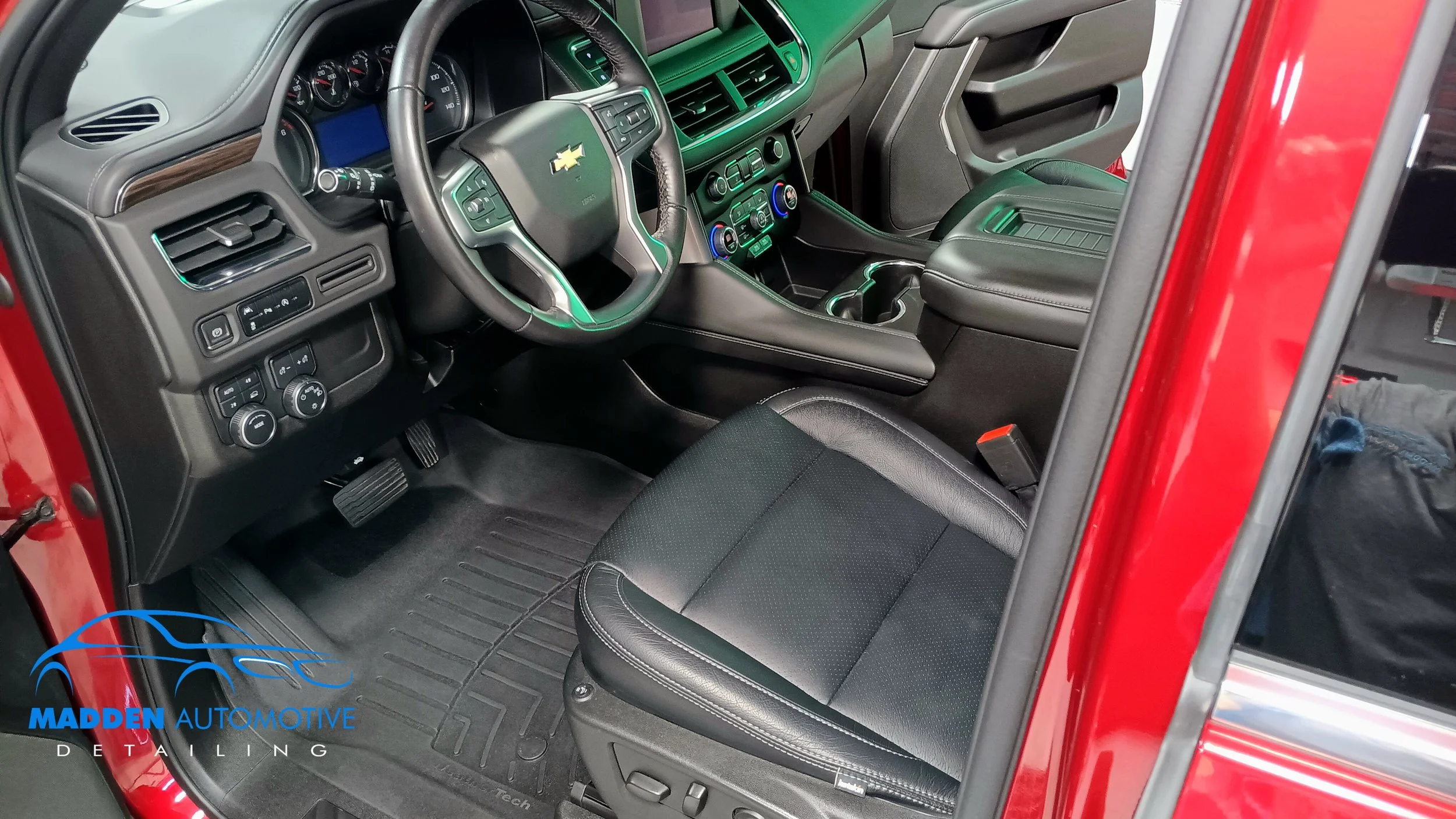 Interior view of a Chevrolet vehicle showing the steering wheel, dashboard, center console, and driver's seat, with Madden Automotive Detailing logo in the lower left corner.