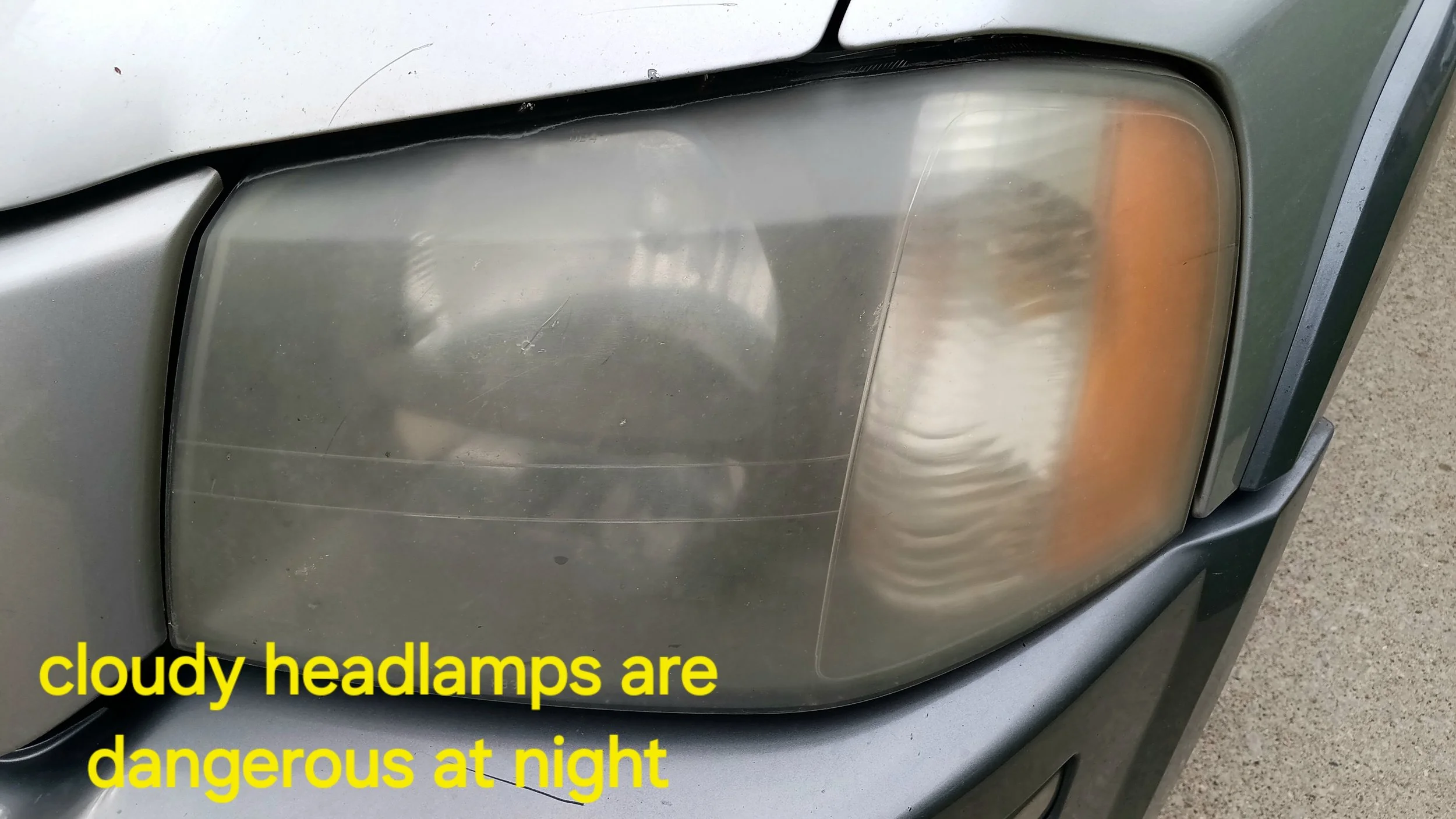 Close-up of a car's headlamp, which is cloudy and yellowed, with text overlaid stating 'cloudy headlamps are dangerous at night'.