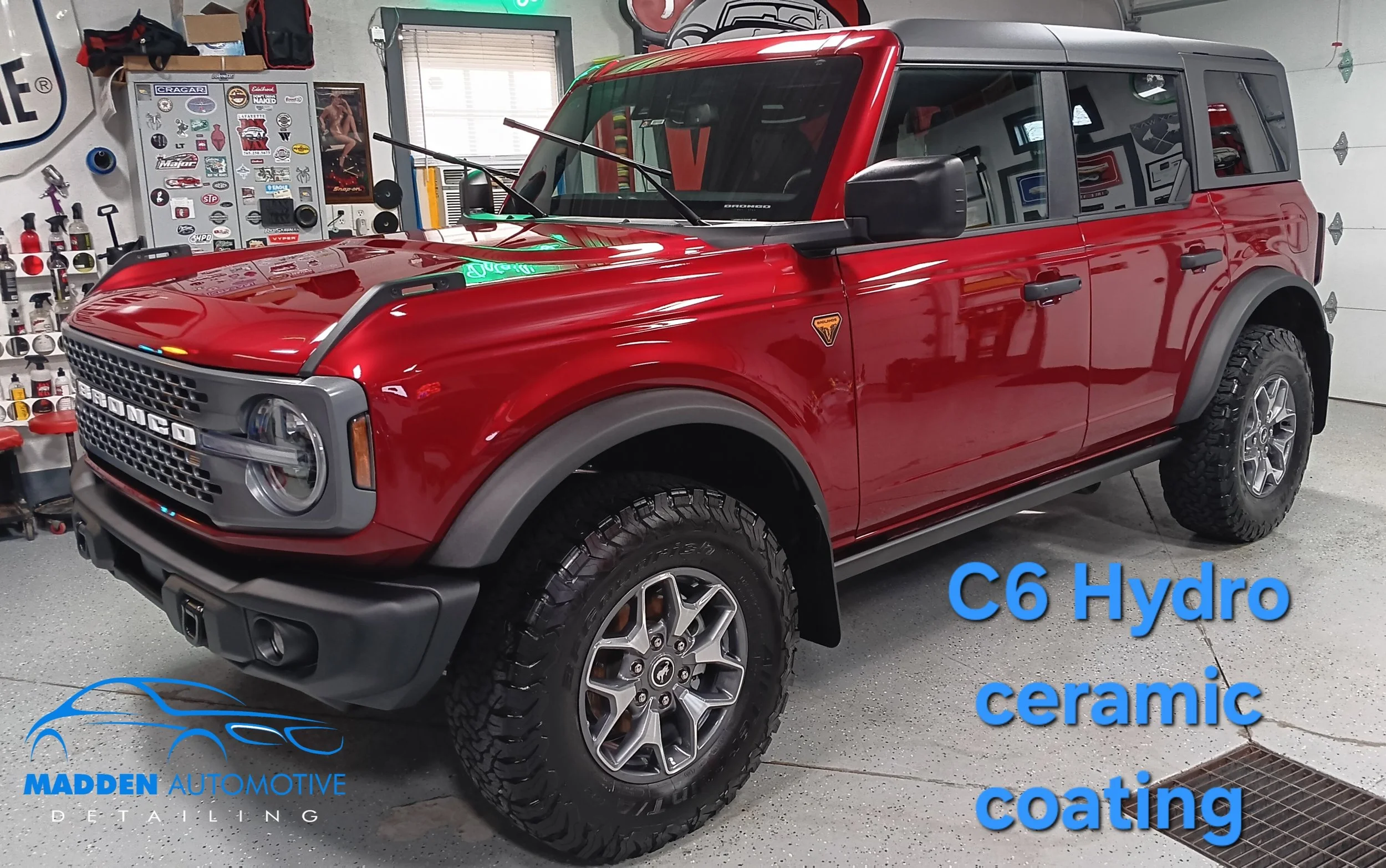 A red Suzuki Bronco SUV parked in a garage with automotive stickers on a wall behind it. Text on the image mentions 'C6 Hydro ceramic coating' and 'Madden Automotive detailing'.