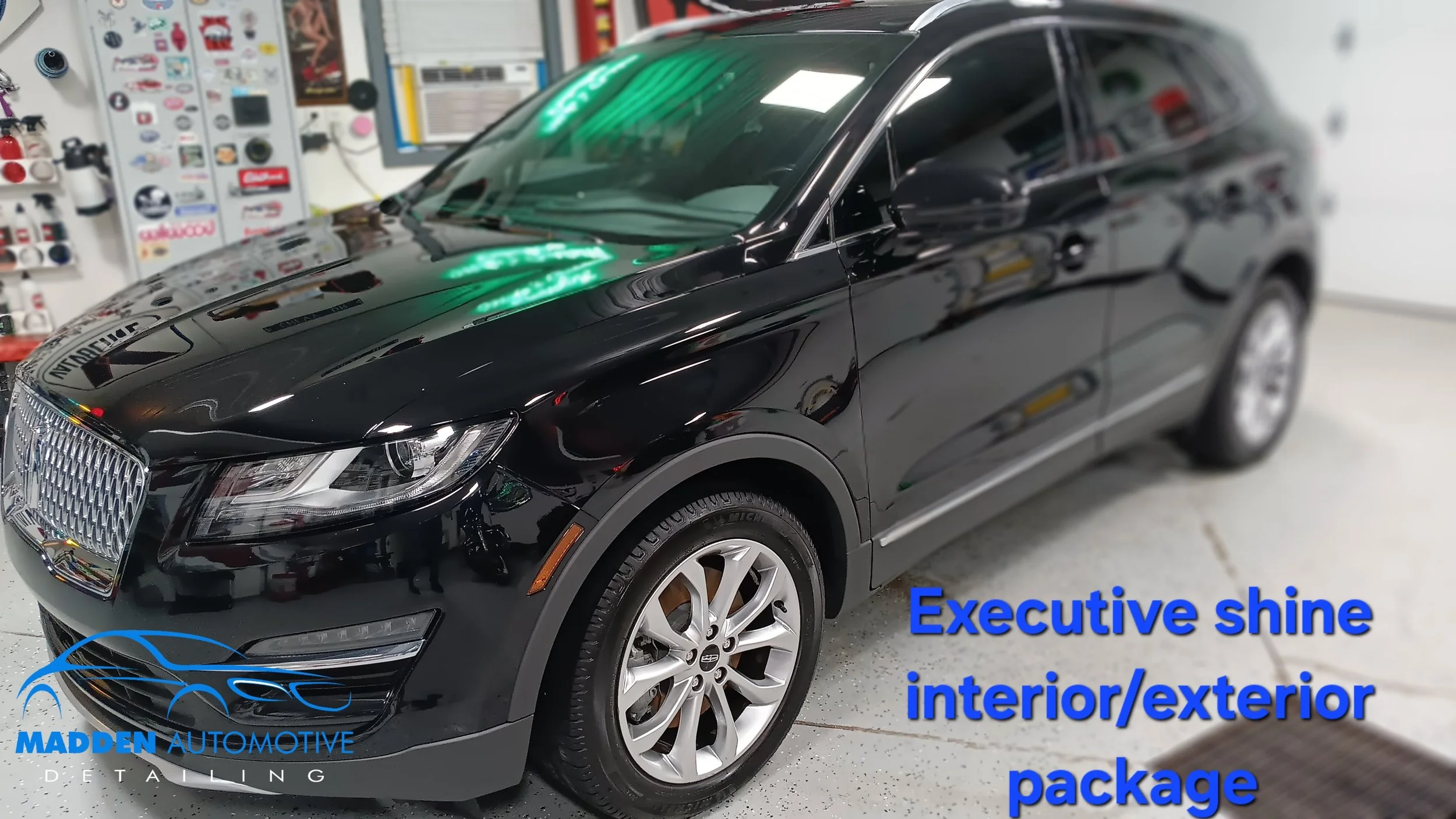 A black luxury vehicle inside a garage with a detail shop background. The car's exterior is shiny and well-polished, and the image has a caption that reads, 'Executive shine interior/exterior package,' along with the Madden Automotive Detailing logo.