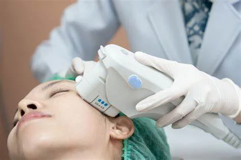 Medical professional with gloves performing a facial treatment on a woman with closed eyes using a handheld device.