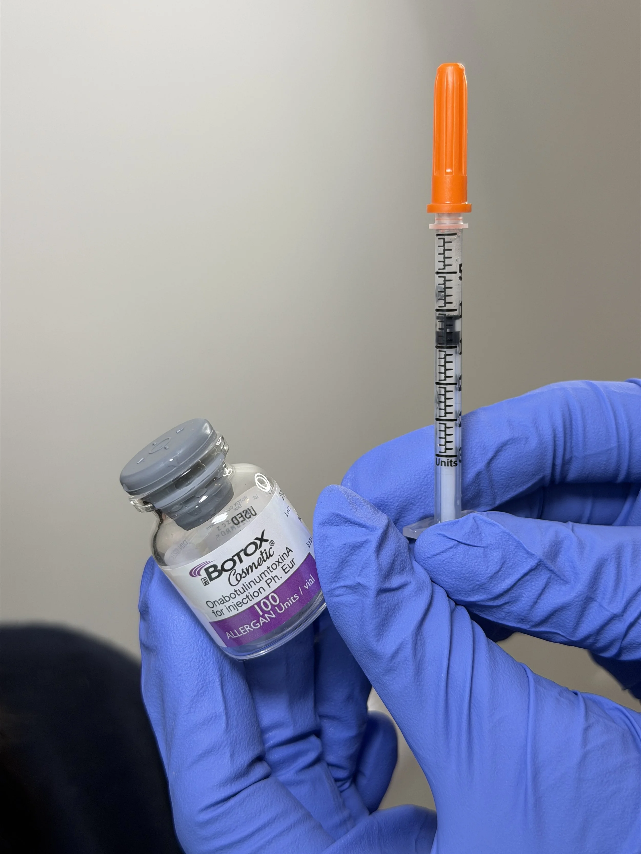 Gloved hands holding a Botox vial and syringe