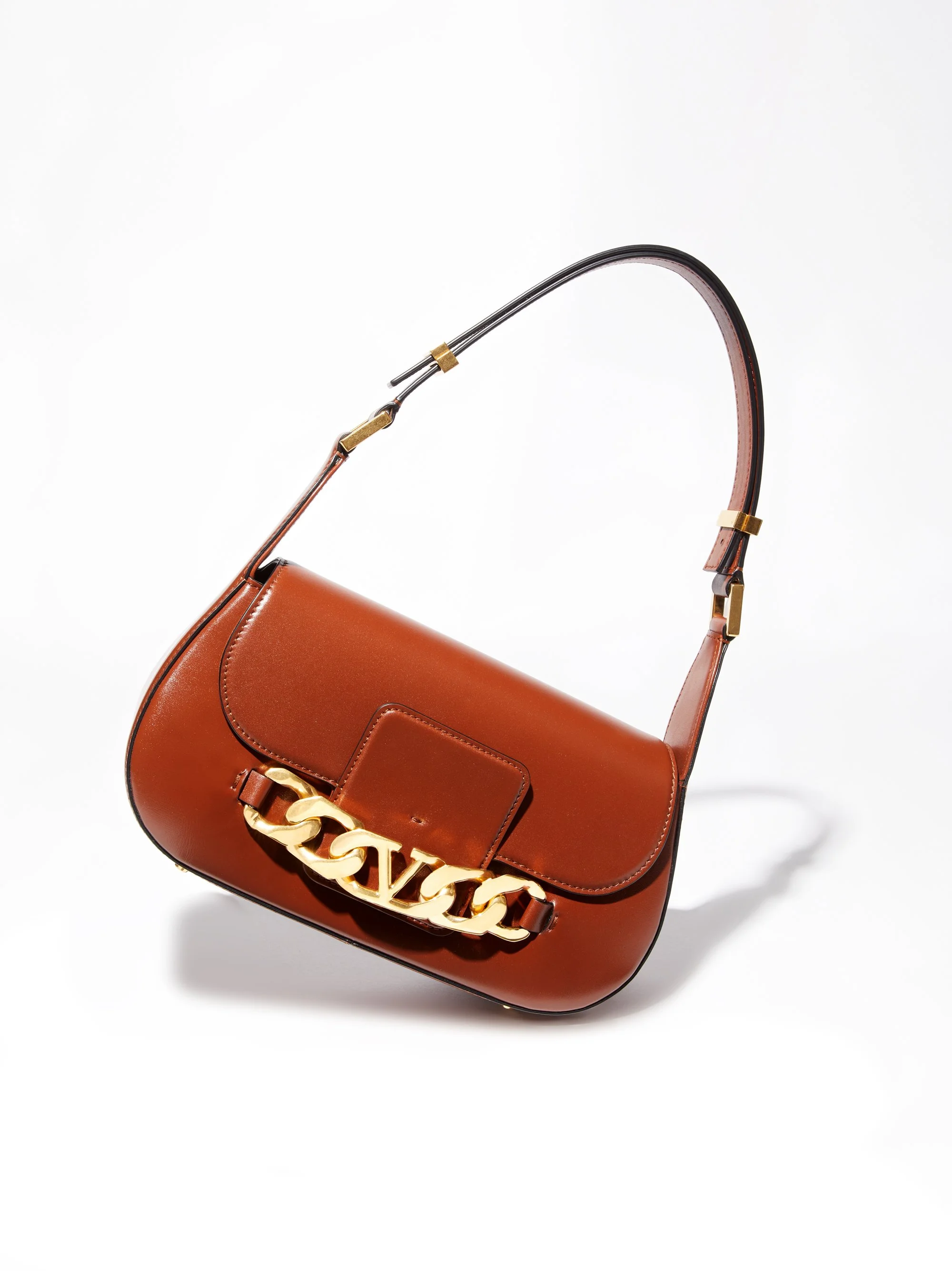 Brown designer shoulder bag with large gold chain detail on the front, isolated on white background.