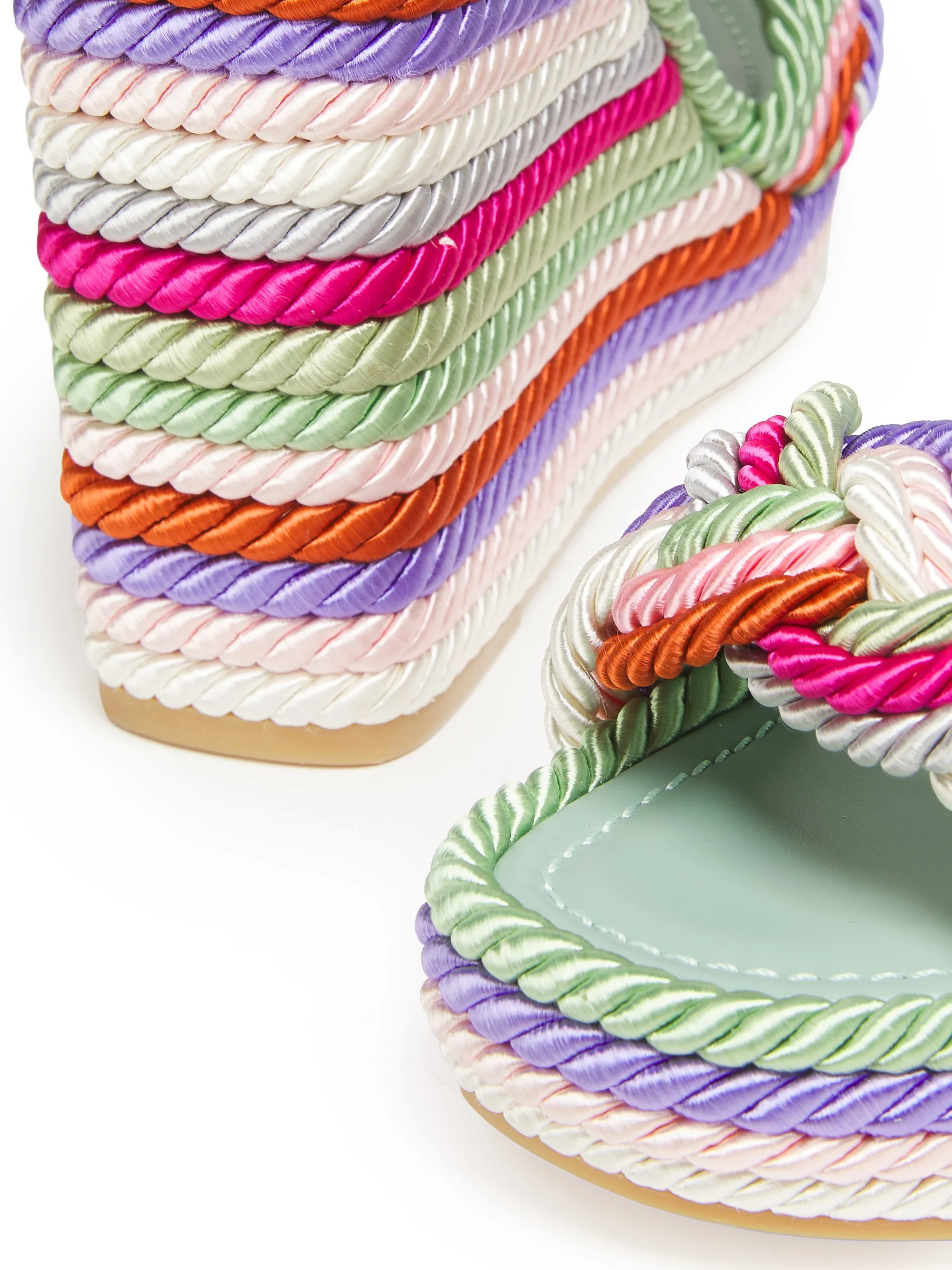 Colorful braided rope bracelets in purple, pink, green, white, gray, and orange, arranged on a pastel green jewelry stand.