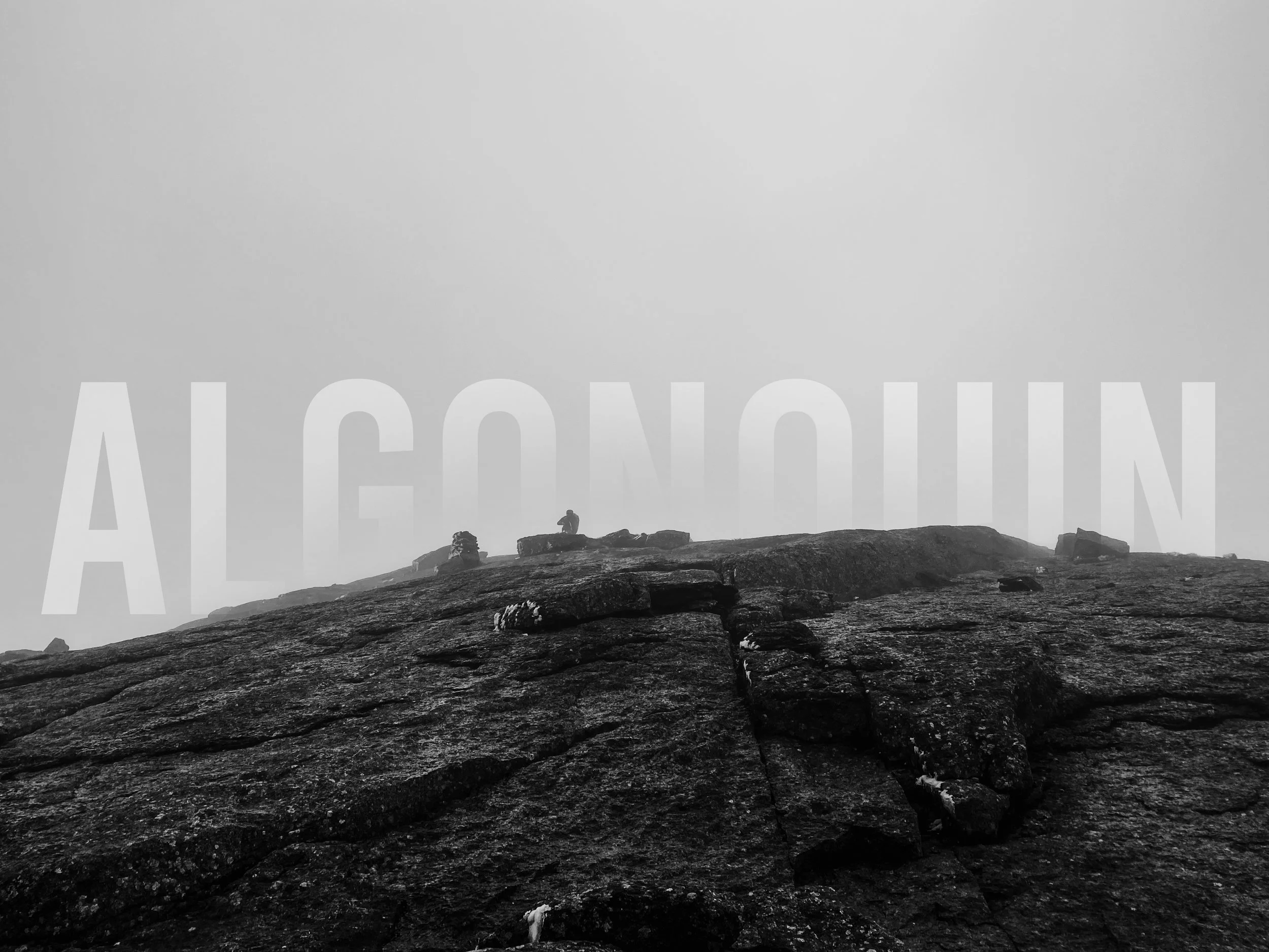 Summit of Algonquin Mountain with Andrew just coming up over the summit in the distance during a storm