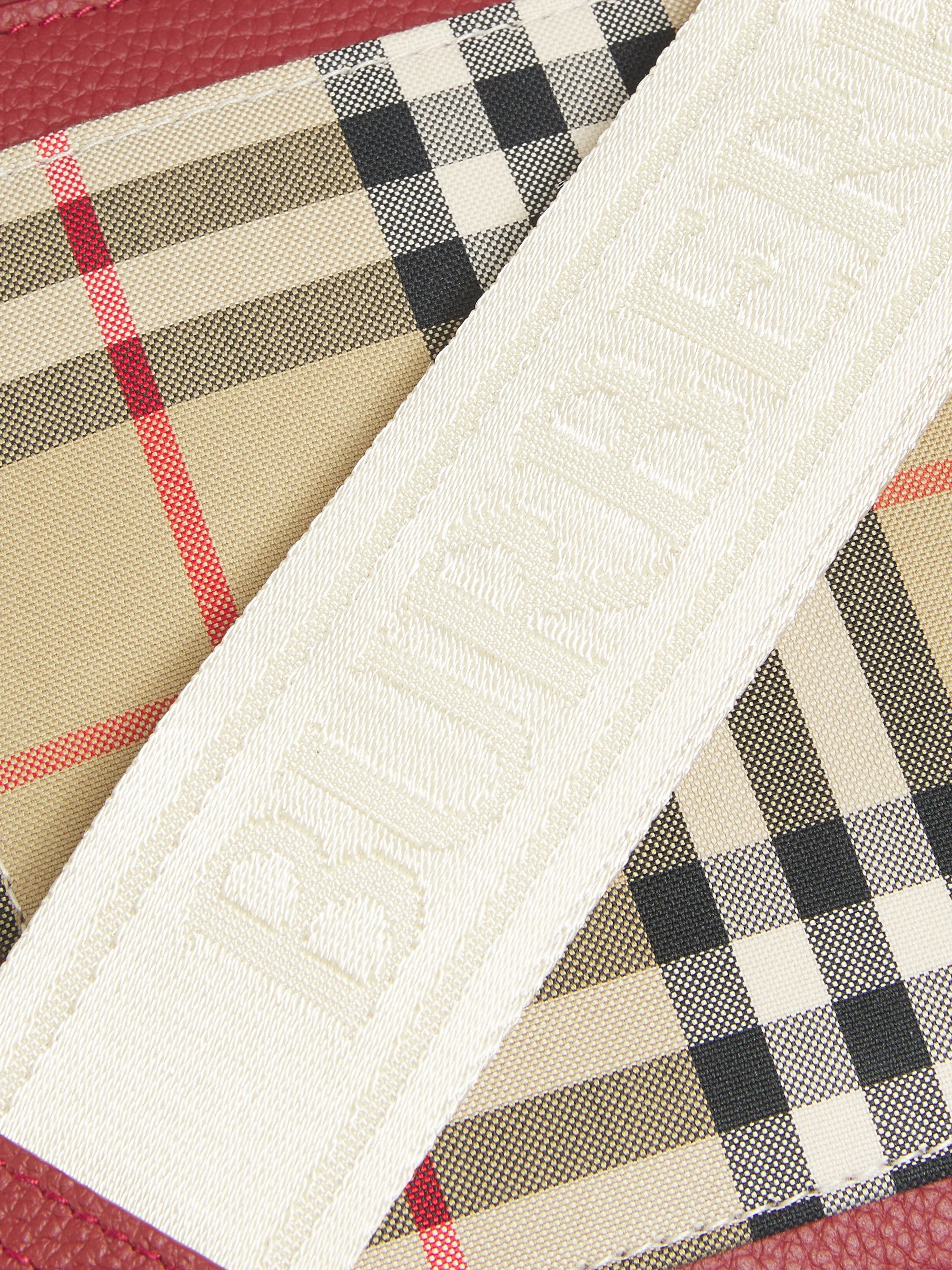 Close-up of a beige and black checkered fabric with a white fabric strap displaying the word "BURBERRY" in embossed letters.