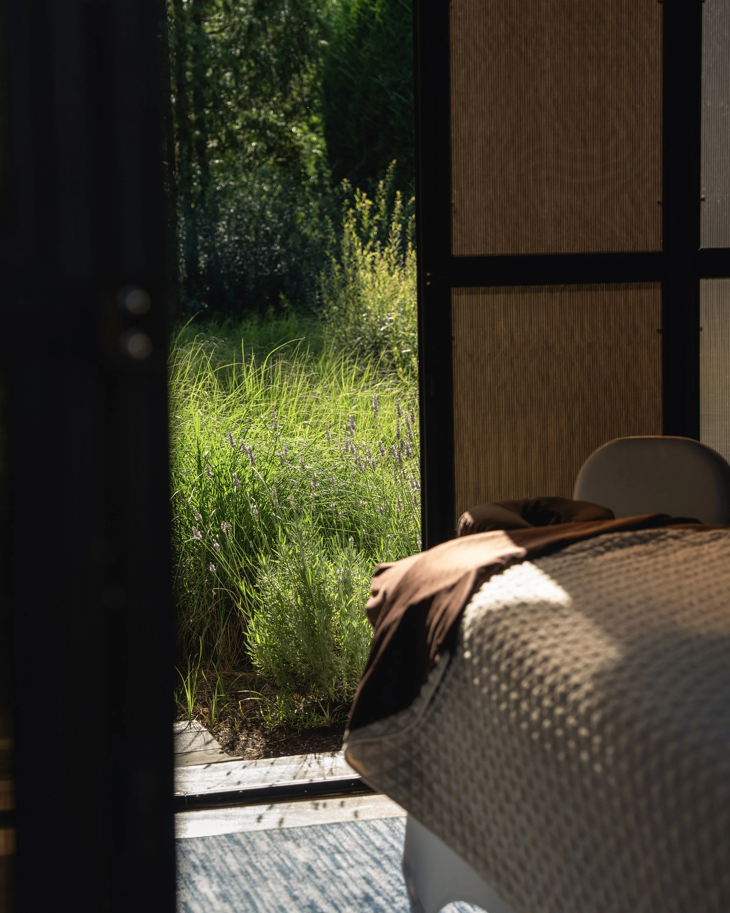 Open door leading from bedroom to grassy garden with sunlight.
