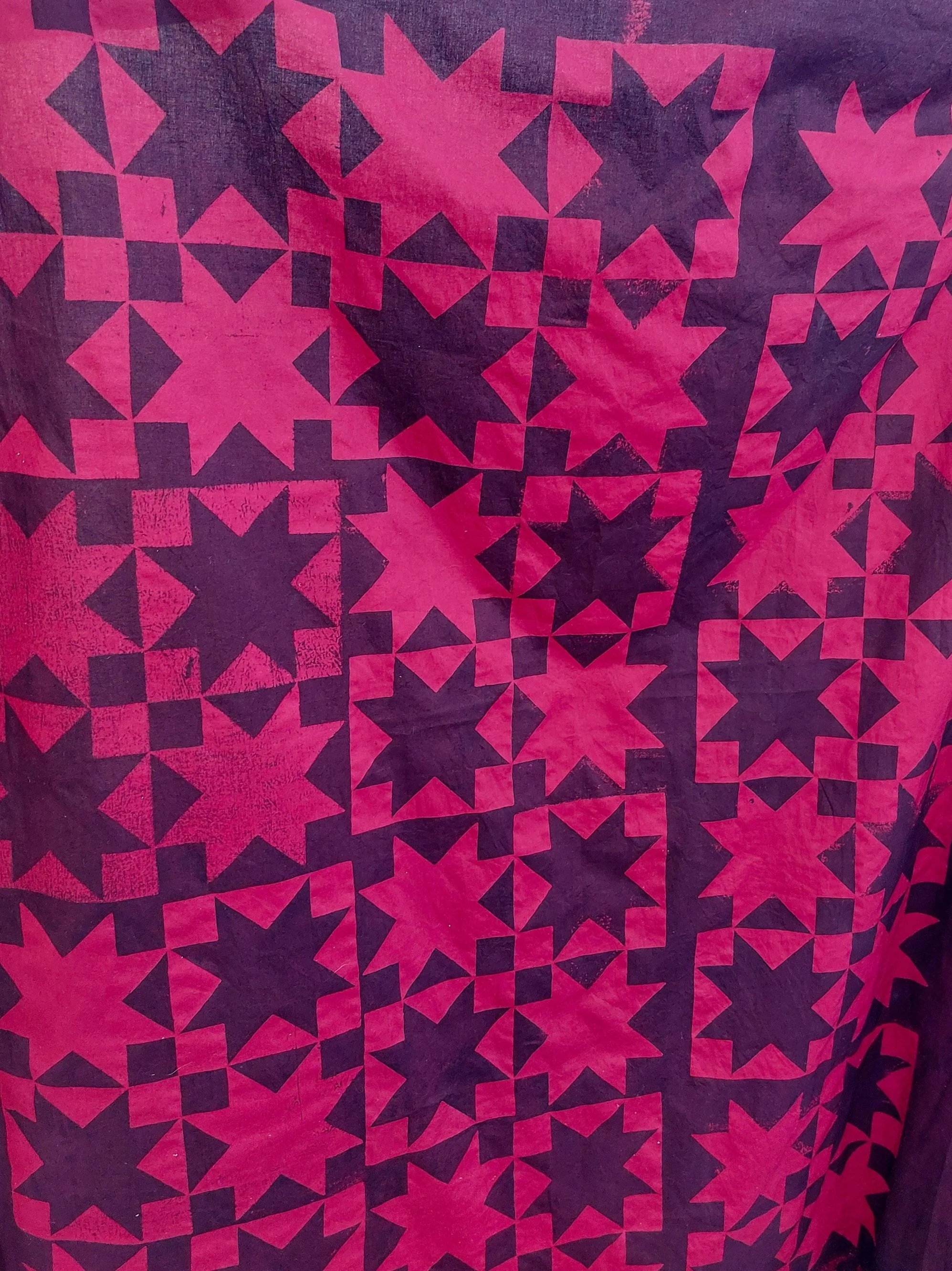 bright and dark red fabric, screenprinted with a quilt pattern.