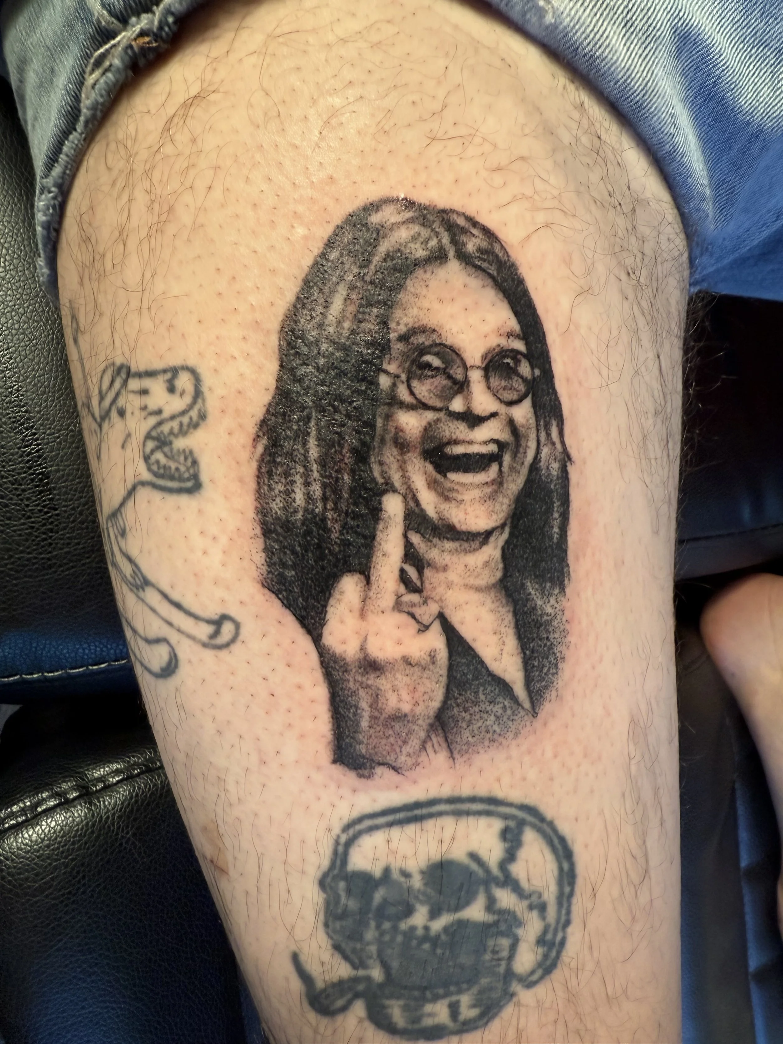 Tattoo of a woman with glasses, smiling and showing her middle finger.