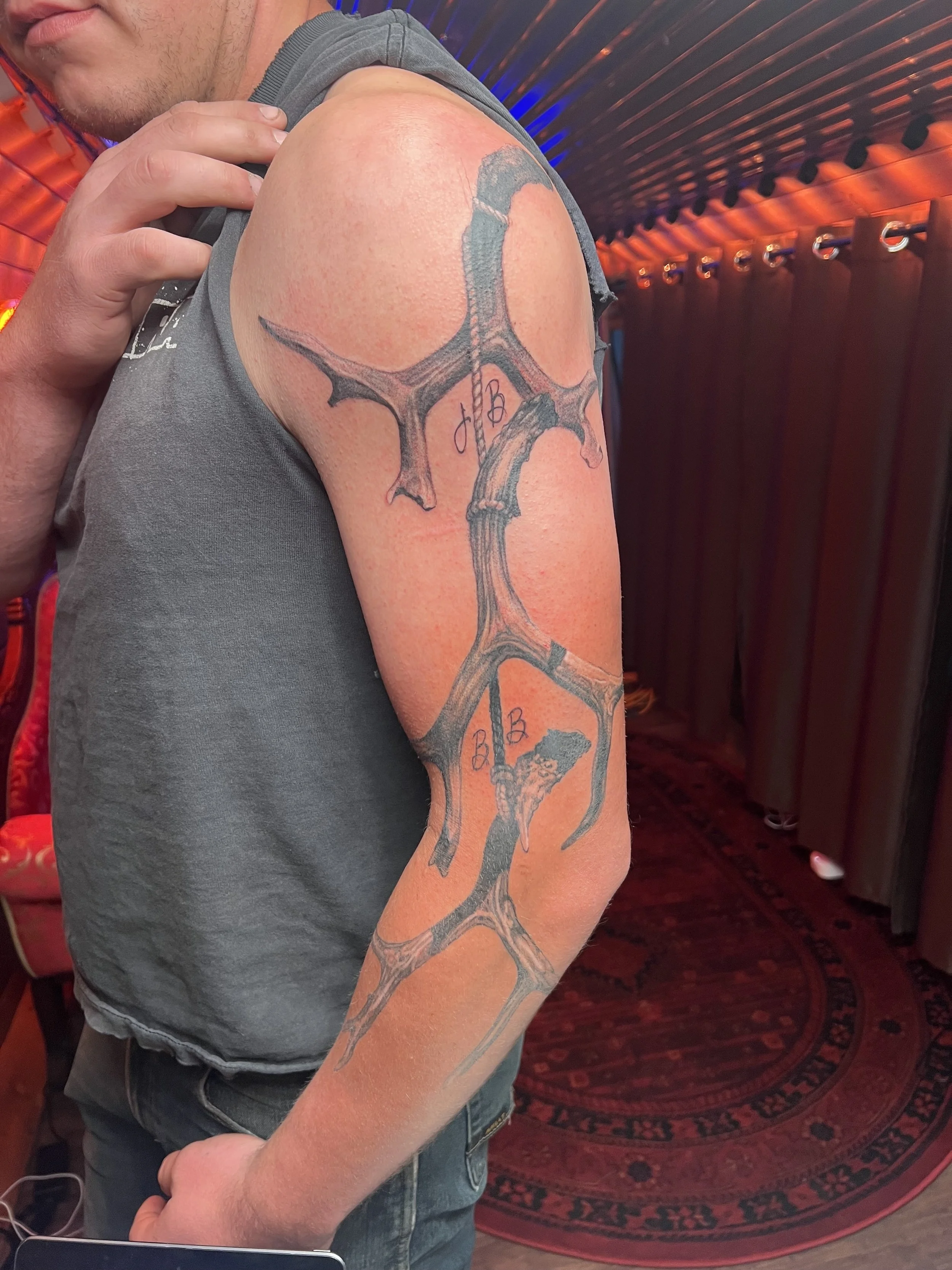 Tattoo of a large, realistic deer antler on a man's upper arm.