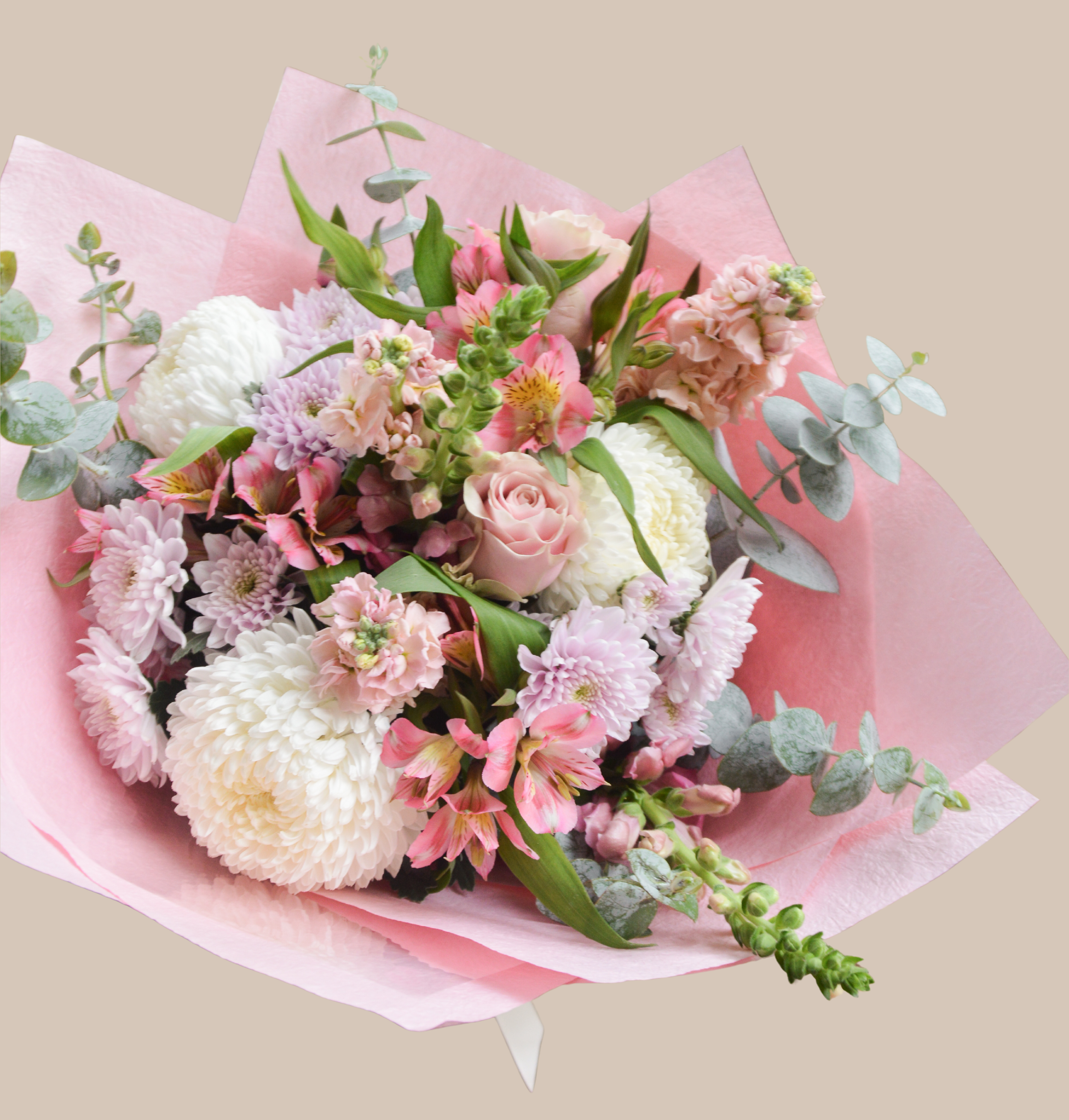 Pink, white, and blush flower bouquet with roses, chrysanthemums, alstroemeria, and eucalyptus in pink wrapping paper.