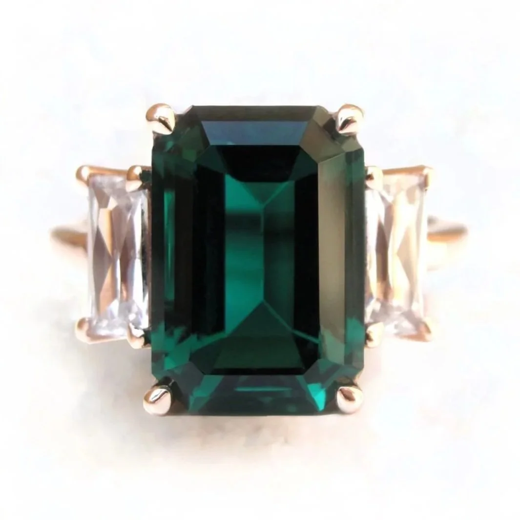 Repurposed jewelry used to create a ring with a large emerald-cut green gemstone and clear rectangular side stones set in a gold band - Custom Jewelry Prosper, McKinney, Frisco Tx.