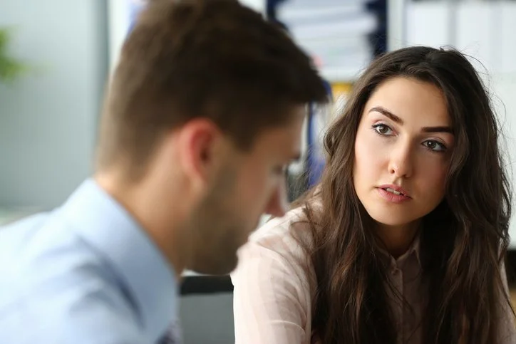 A man and woman in relationship counseling in Denver look at each with a serious face.