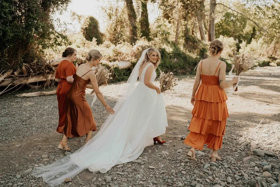 Bride with long train walking with bridesmaids wearing copper coloured dresses from Kirsty & Cameron's wedding at Stonebridge photographed by Sarah Clements Photography