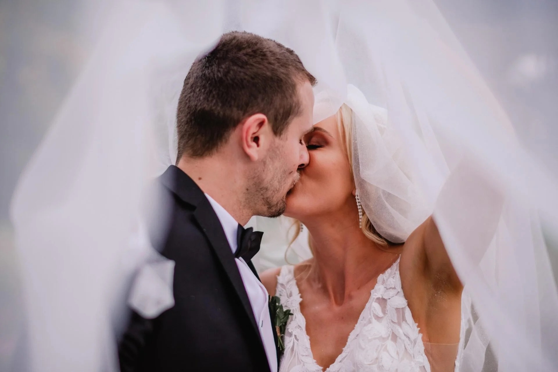 Bride and groom kissing under white veil from Cushla & Harry's wedding at Pemberton Gardens photographed by Joseph O’Sullivan Photography