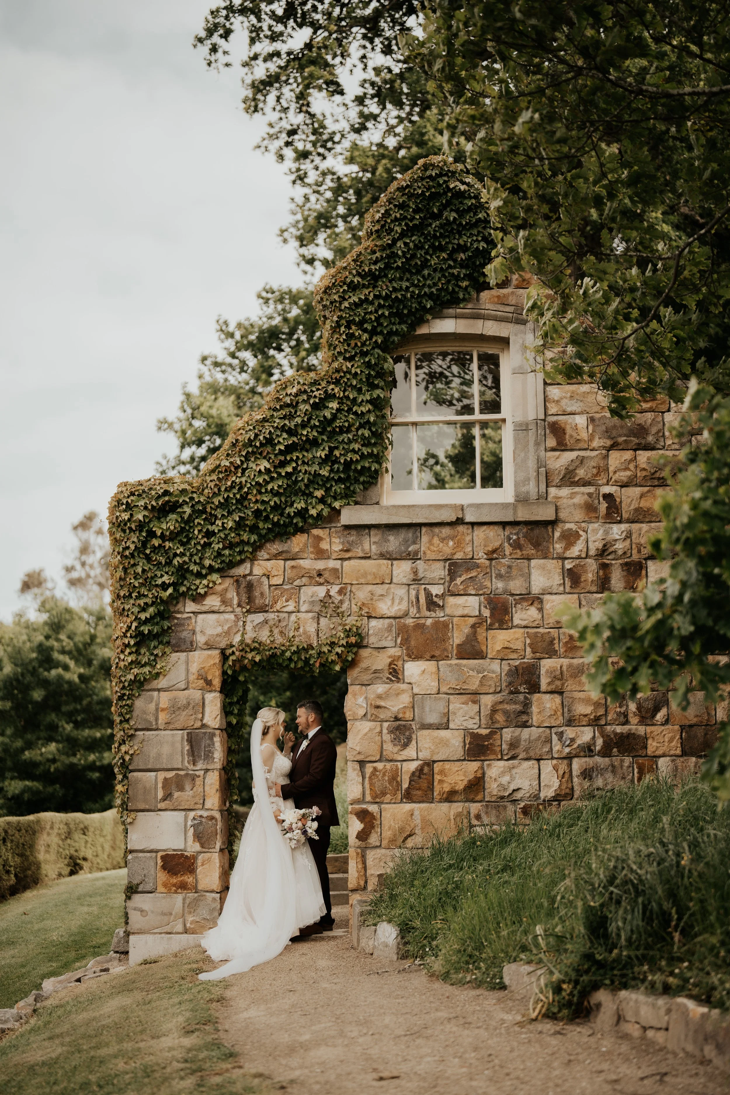 Bride and groom in doorway of stone folly from Emma & Josh's wedding at Ōhinetahi Gardens and Milton St Substation photographed by Sarah Clements Photography.jpg