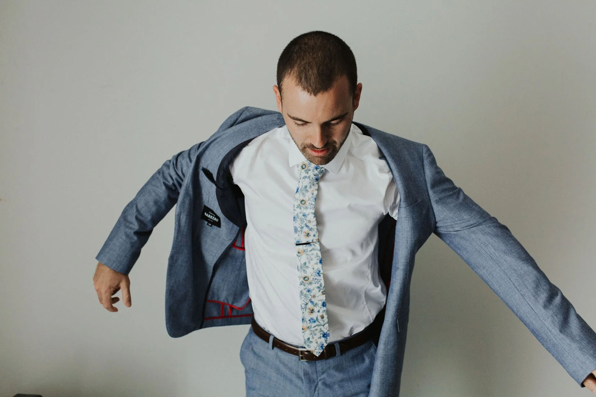Groom putting on his blue suit jacket from Jen & Lewis's wedding at Cossars Wineshed at Tai Tapu photographed by Sophie Isabella Photo