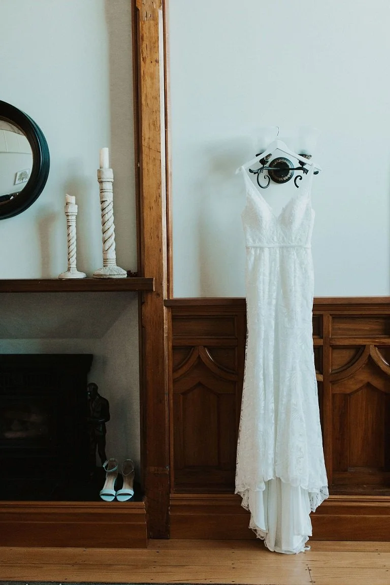 Wedding dress hanging up in historic room from Jen & Lewis's wedding at Cossars Wineshed at Tai Tapu photographed by Sophie Isabella Photo