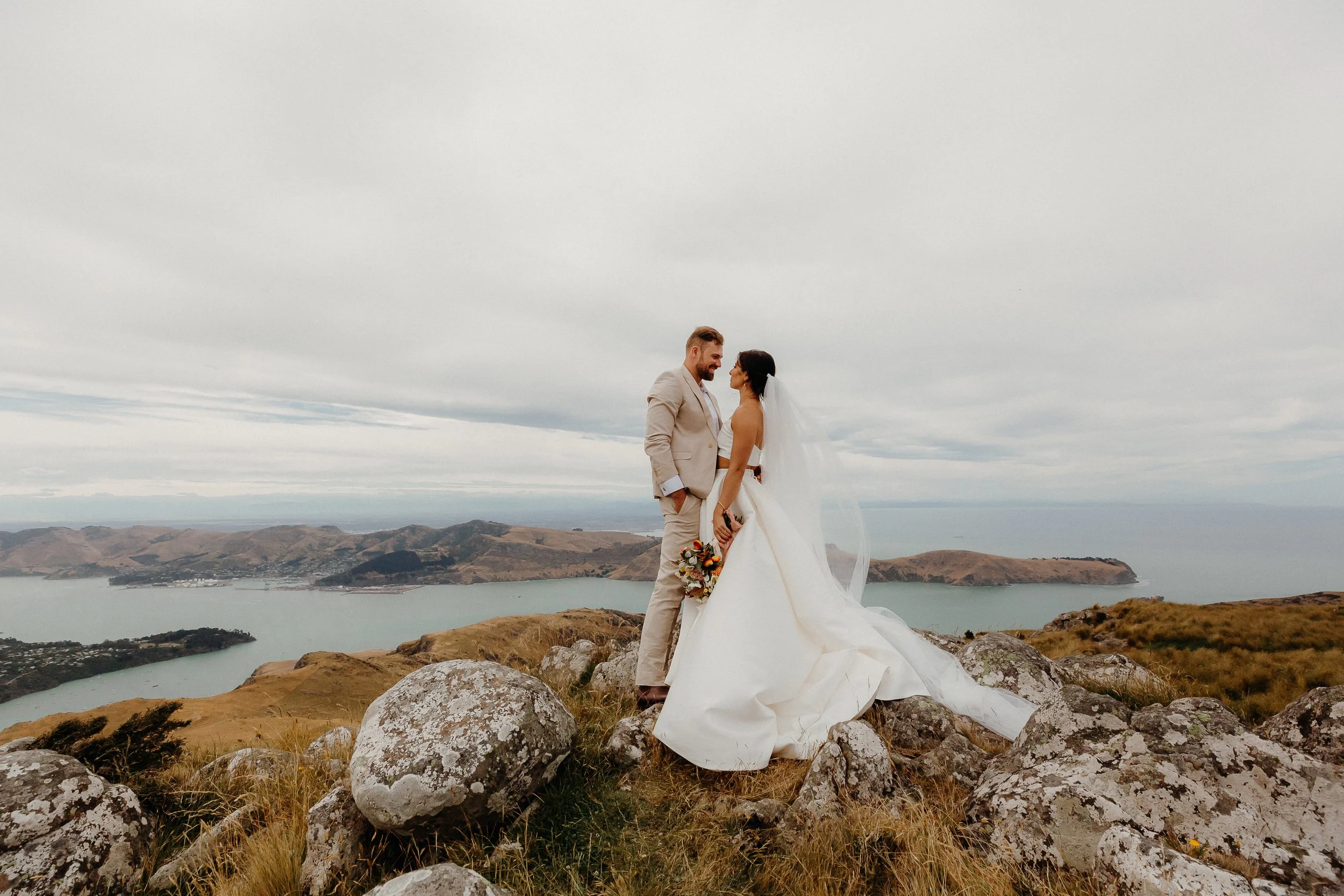 Contemporary bride and groom amongst rocks and tussock from Michelle and Sam's wedding at The Port Hills photographed by Koru Photography