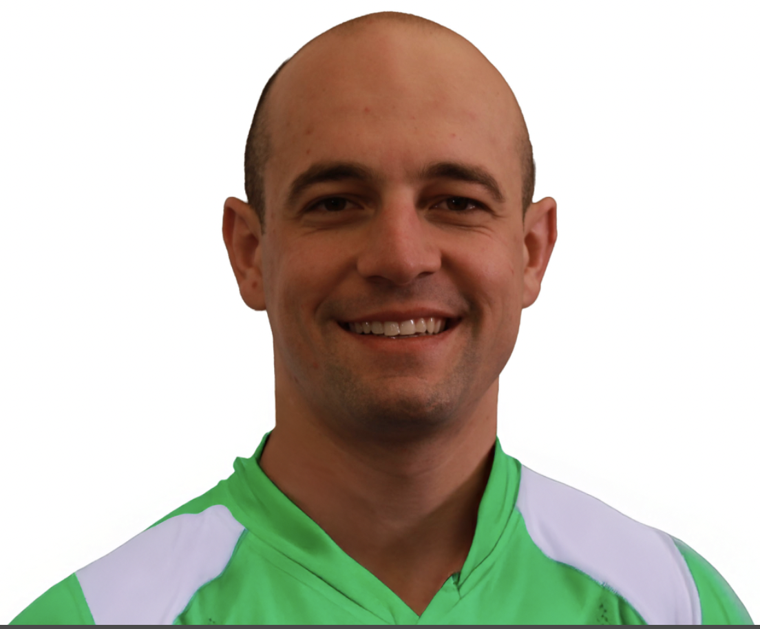 Headshot of a smiling man with a shaved head, wearing a green and white sports jersey against a plain background.