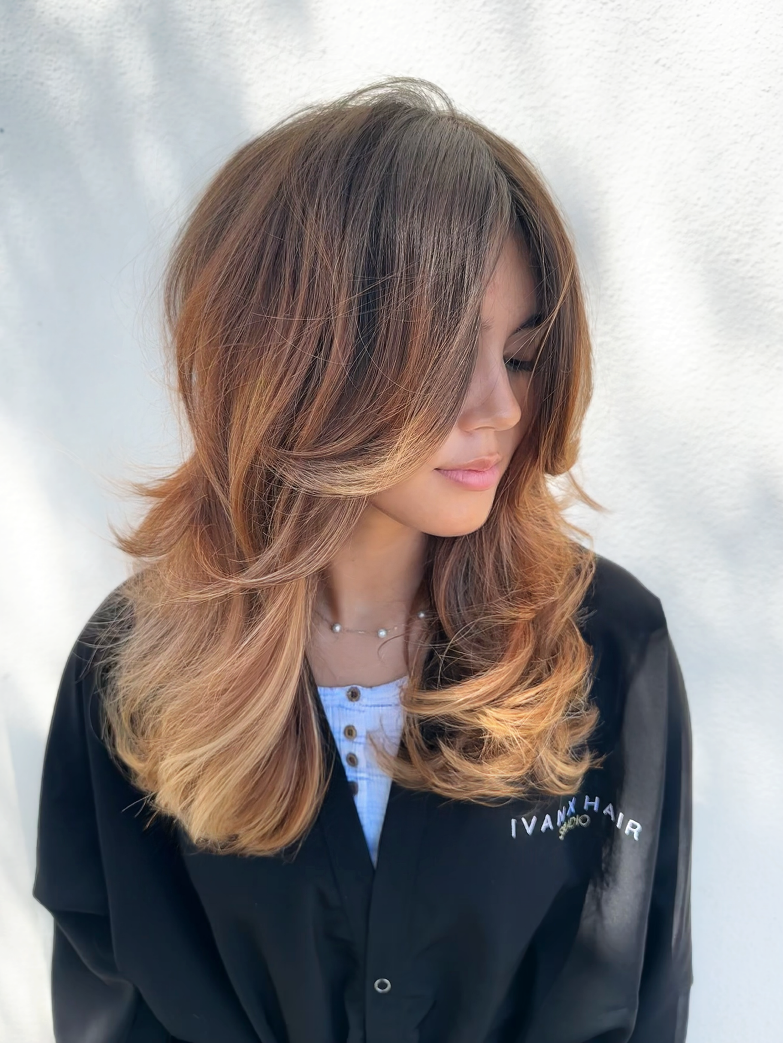 A long layered signature haircut complete with a bouncy 90s blowout and face-framing internal layers, featuring dimensional brunette-to-blonde balayage, at Ivan X Hair in Kennewick, Washington.