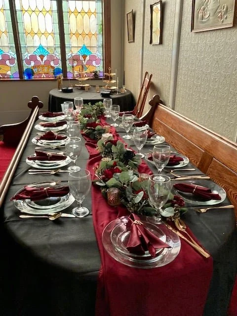 Elegant table setting with black and red decor, stained glass window in background