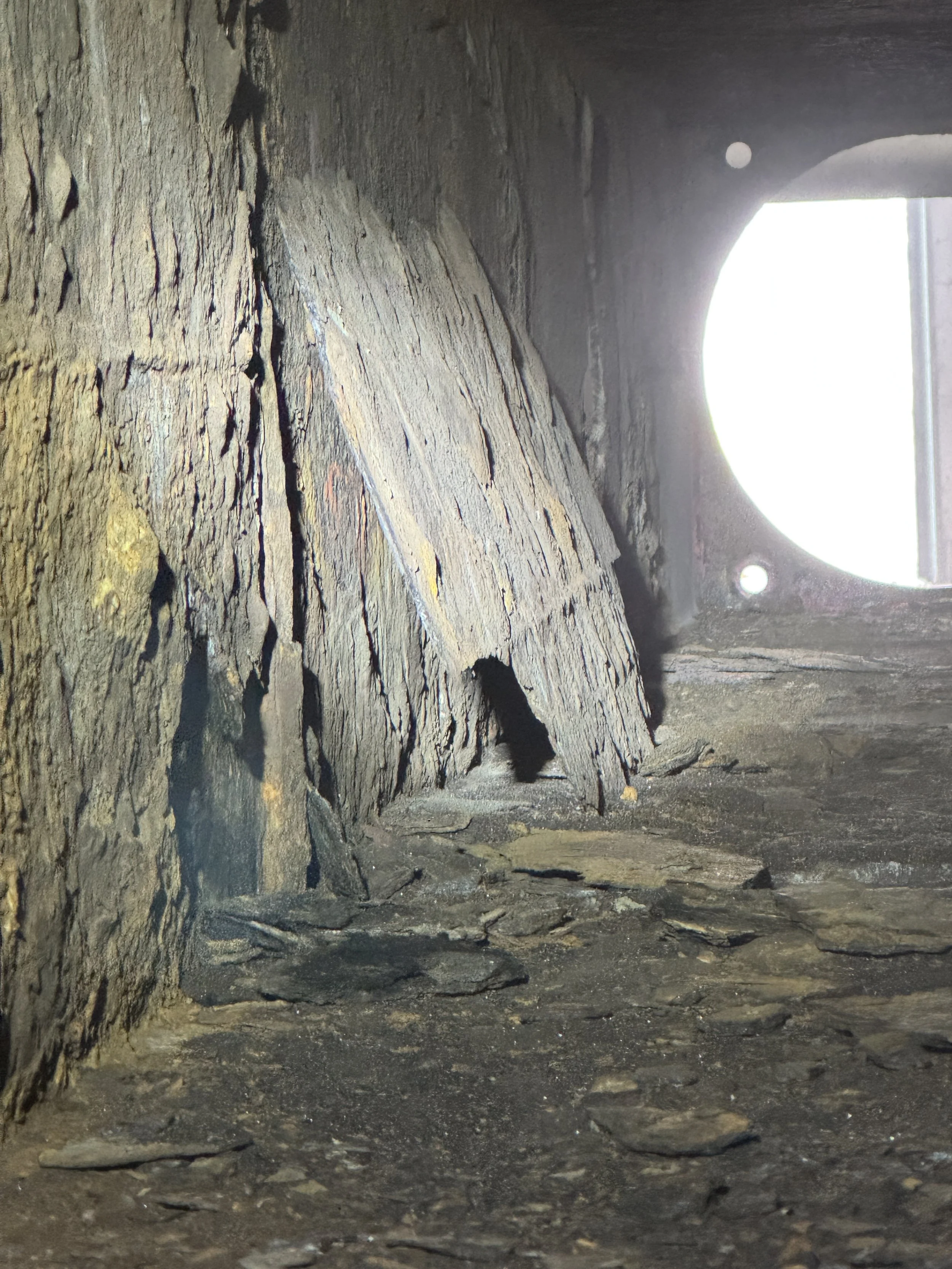 sand blasting inside, Close-up of the interior of a tunnel with rough, textured rock walls and a dirt floor, illuminated by a bright opening at the end.