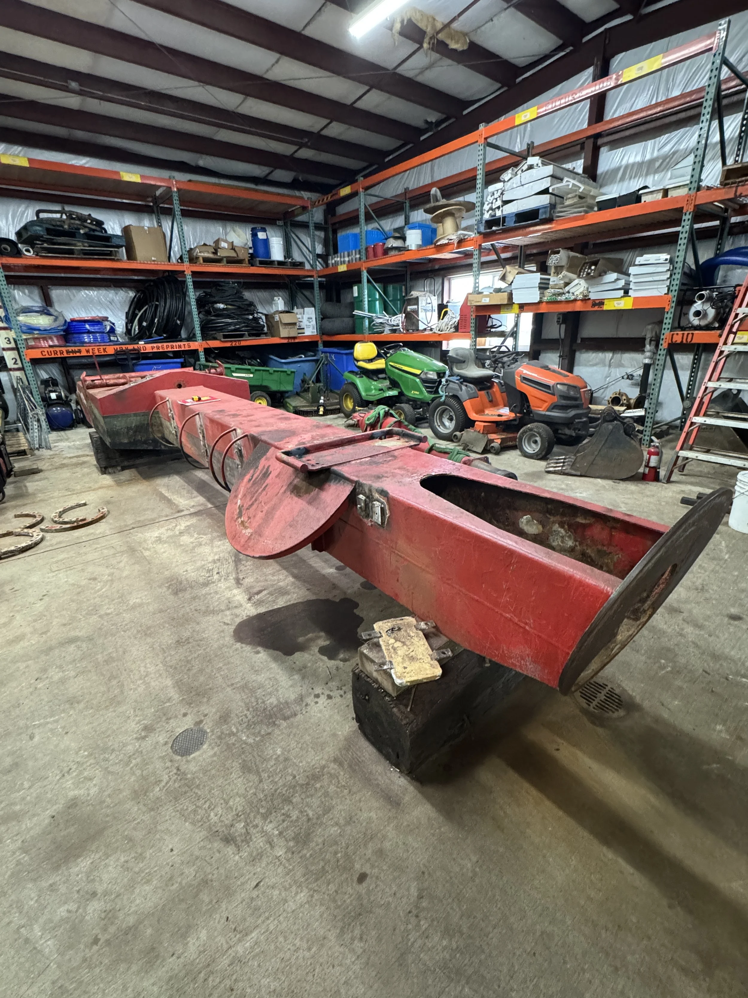 to be sand blasted. stored inside a warehouse, with shelving units holding equipment and tools in the background, including lawn mowers and boxes.
