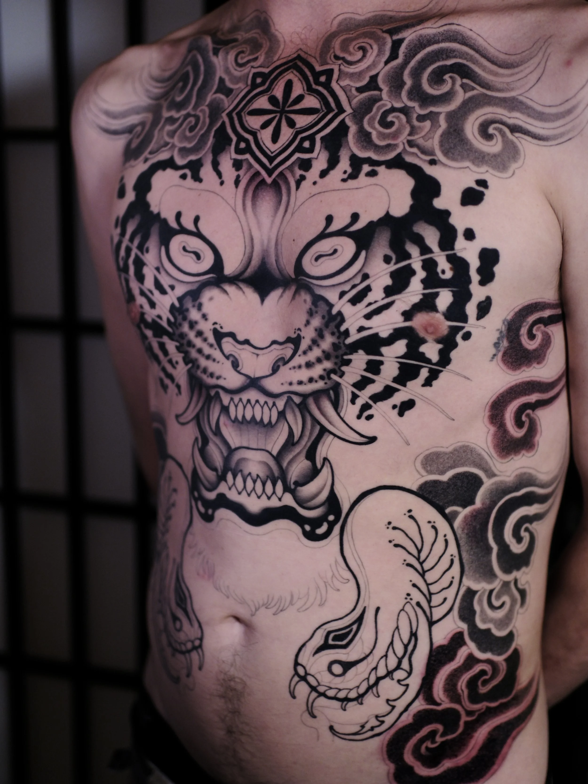 Tattoo of a dragon and clouds on a person's chest and arm.