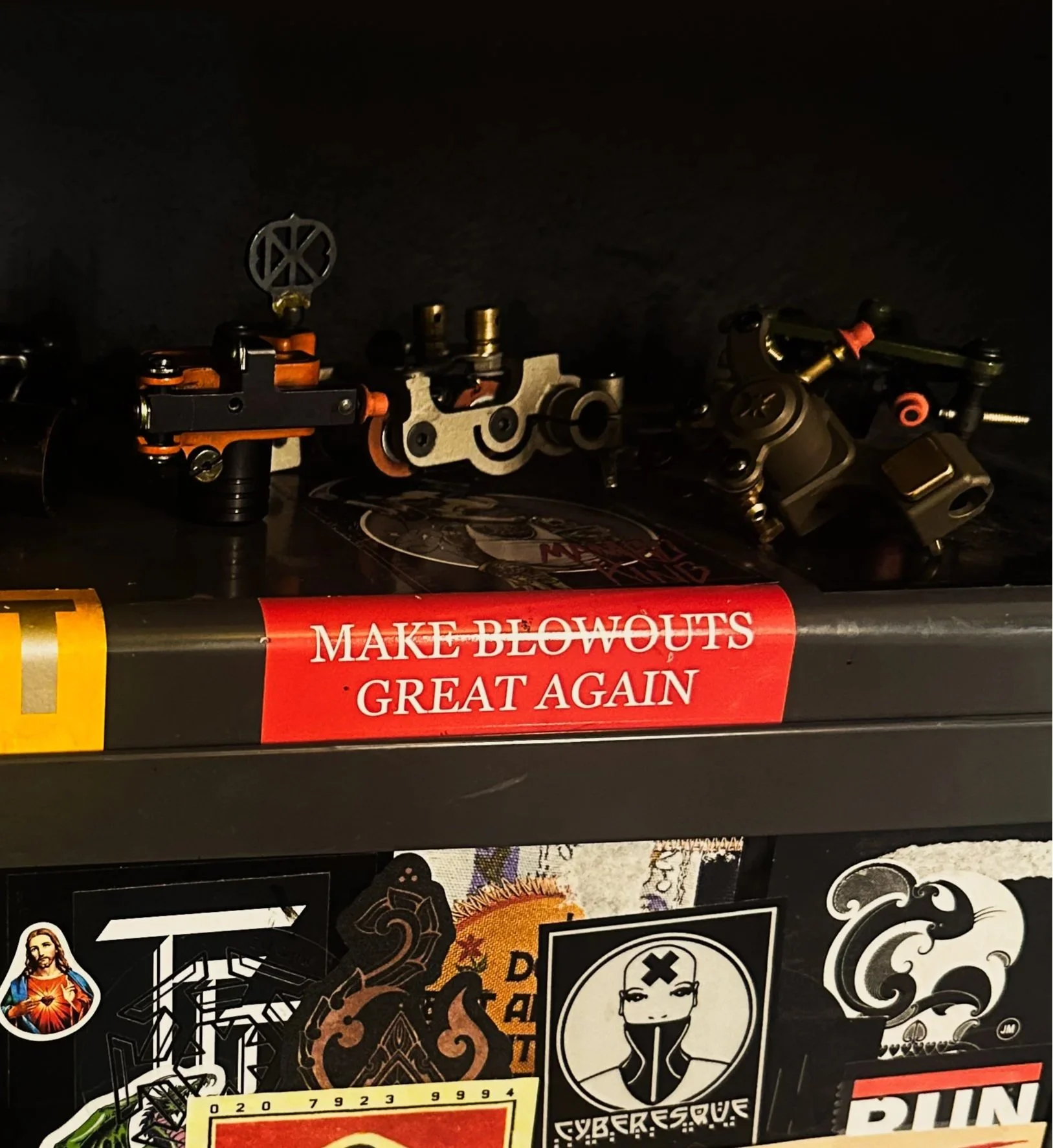 Close-up of a black toolbox with red and white stickers, including a prominent one that says 'MAKE BLOWOUTS GREAT AGAIN' in red text on a white background, and various decals and stickers on the lower part of the toolbox.